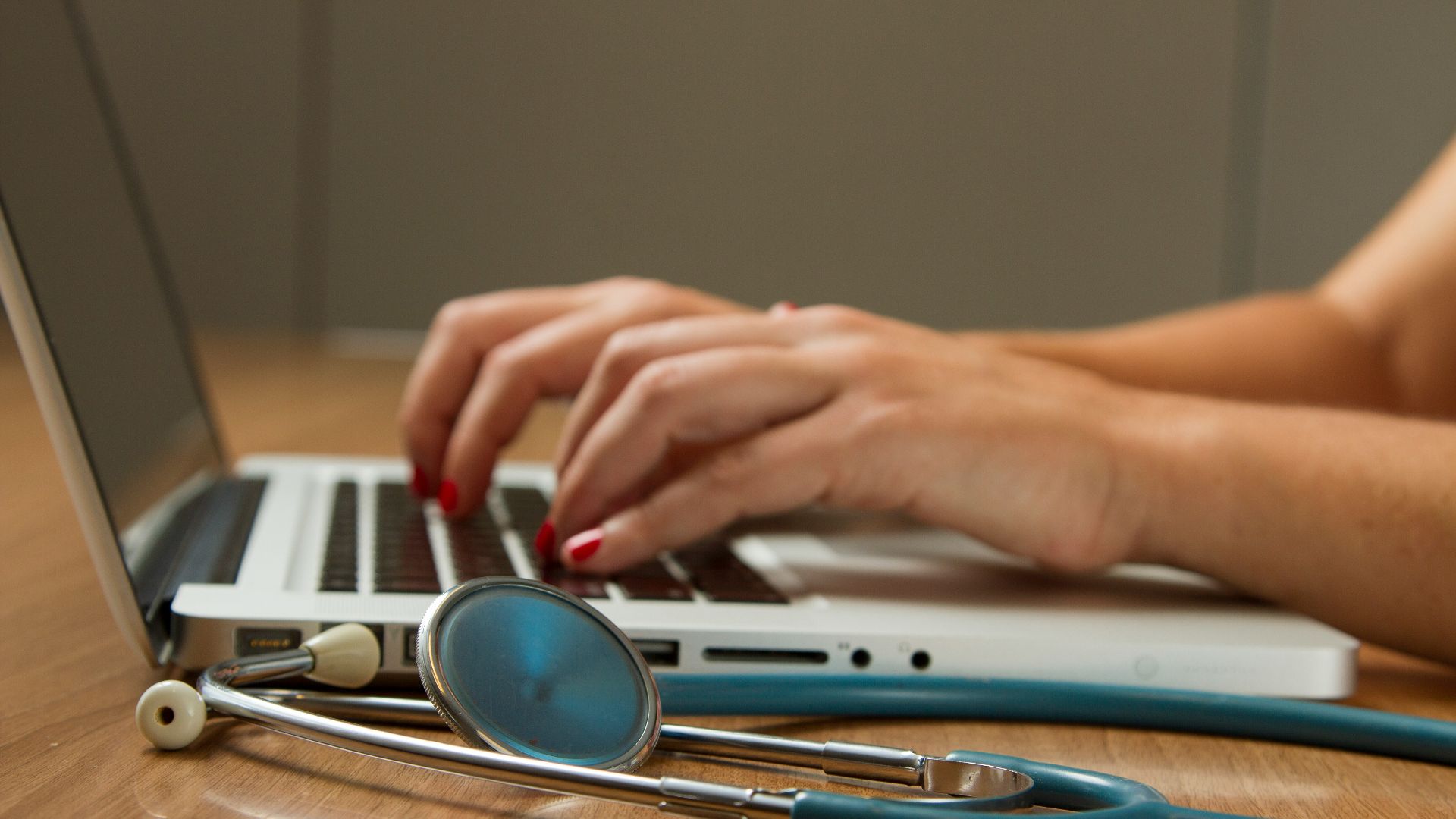 person sitting while using laptop computer and green stethoscope near