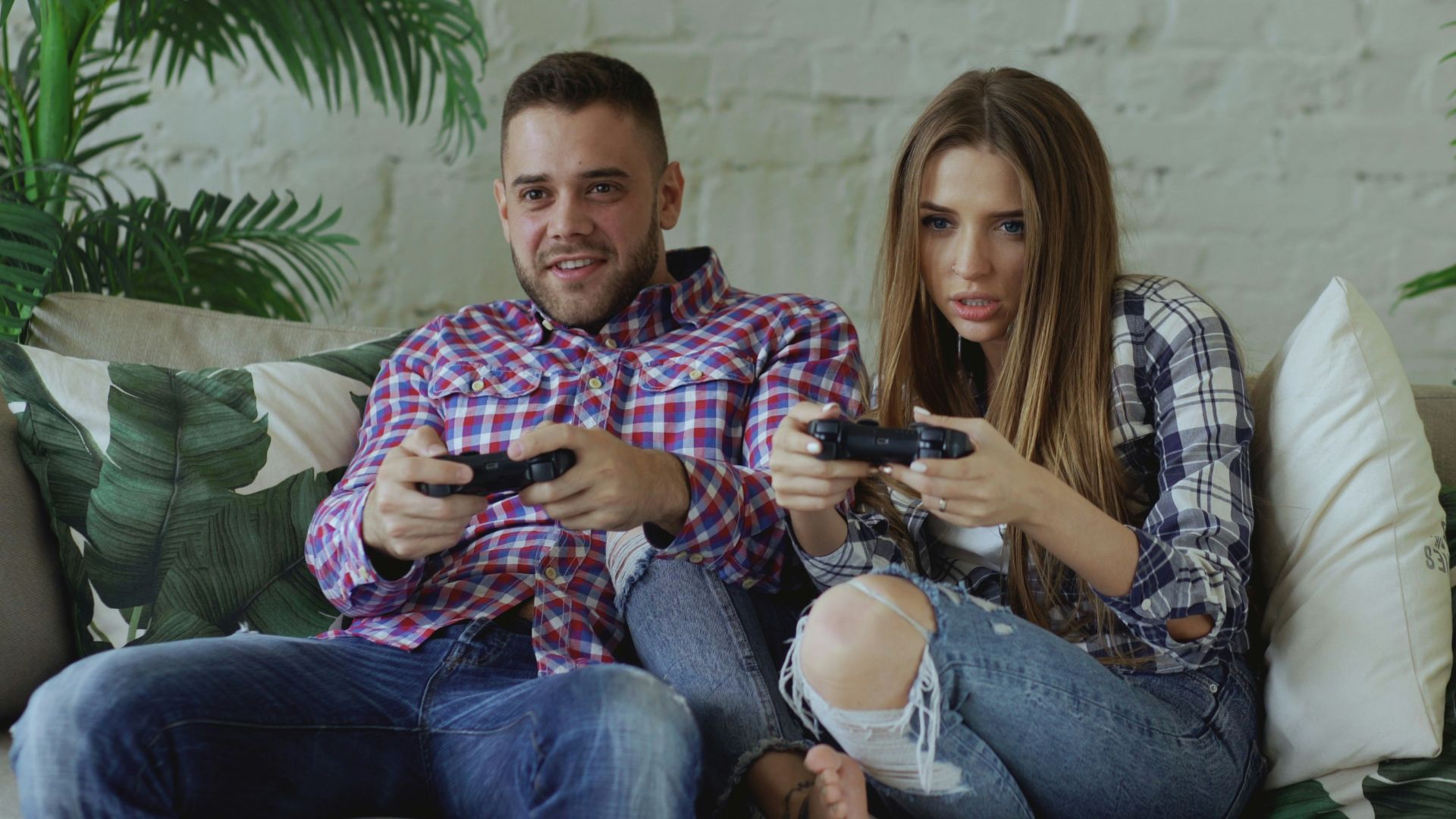 Couple playing video games on sofa