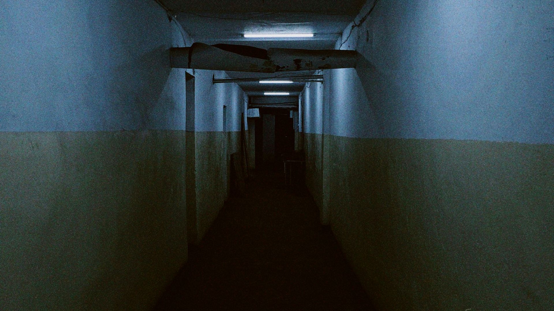 a long dark hallway with a light at the end