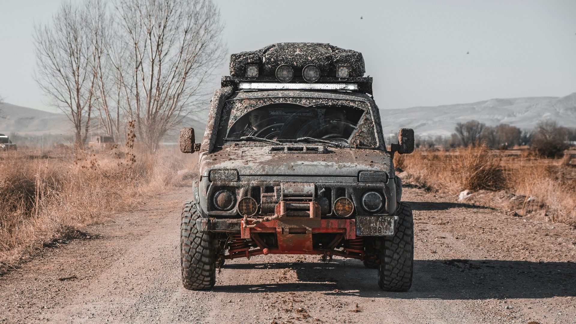 a dirty truck driving down a dirt road