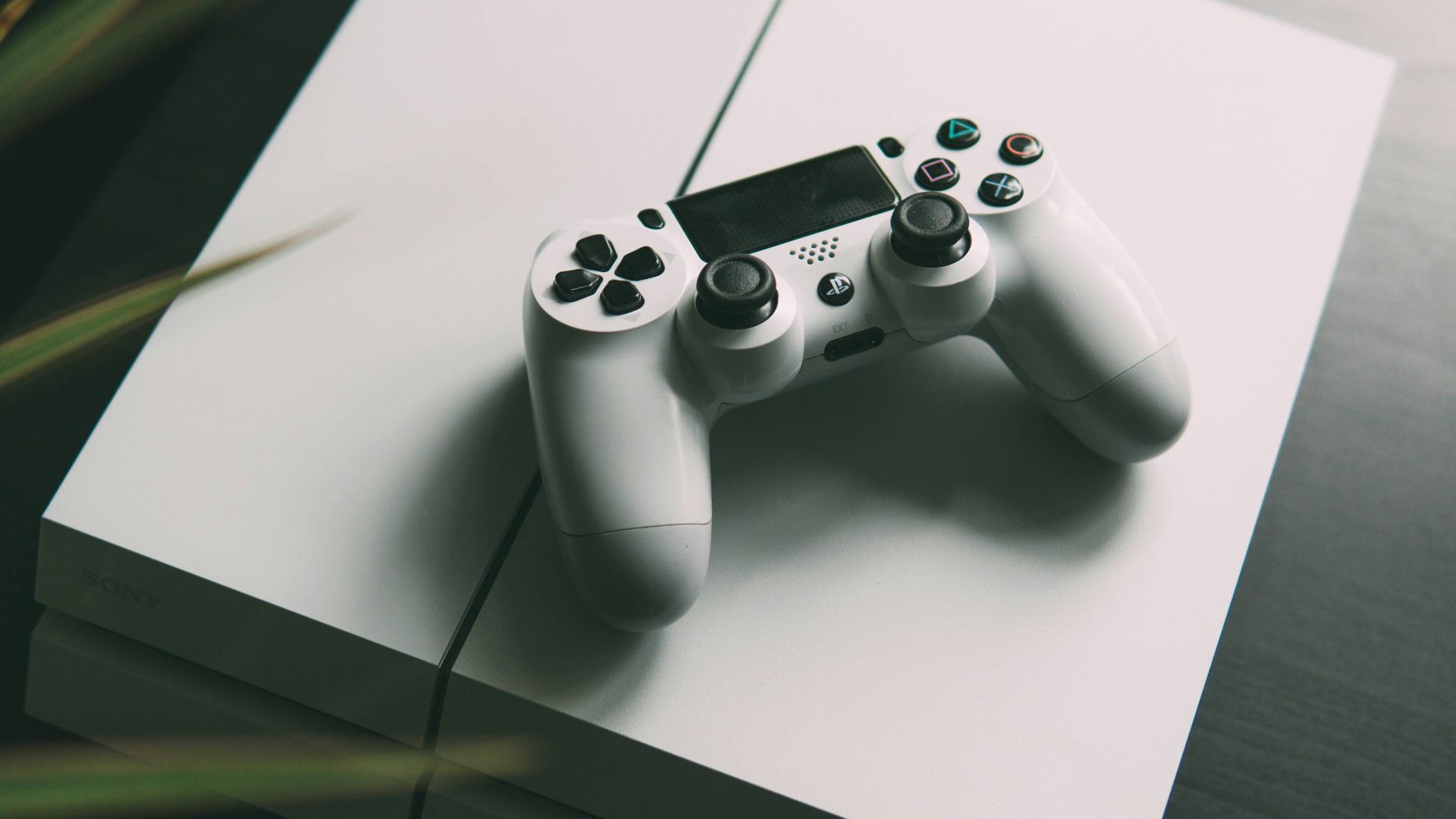 selective focus photography of white Sony PS4 console with wireless controller