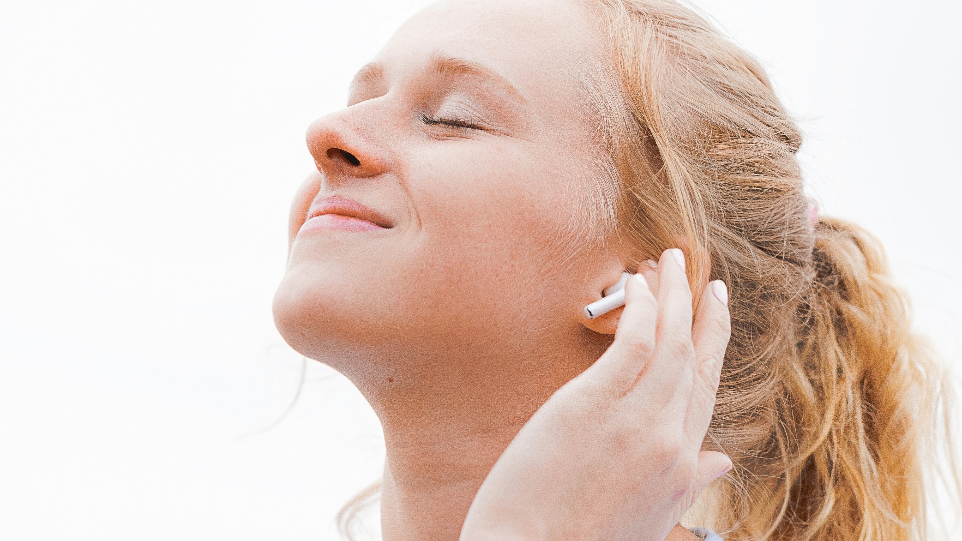 woman in white crew neck shirt covering her face with her hand