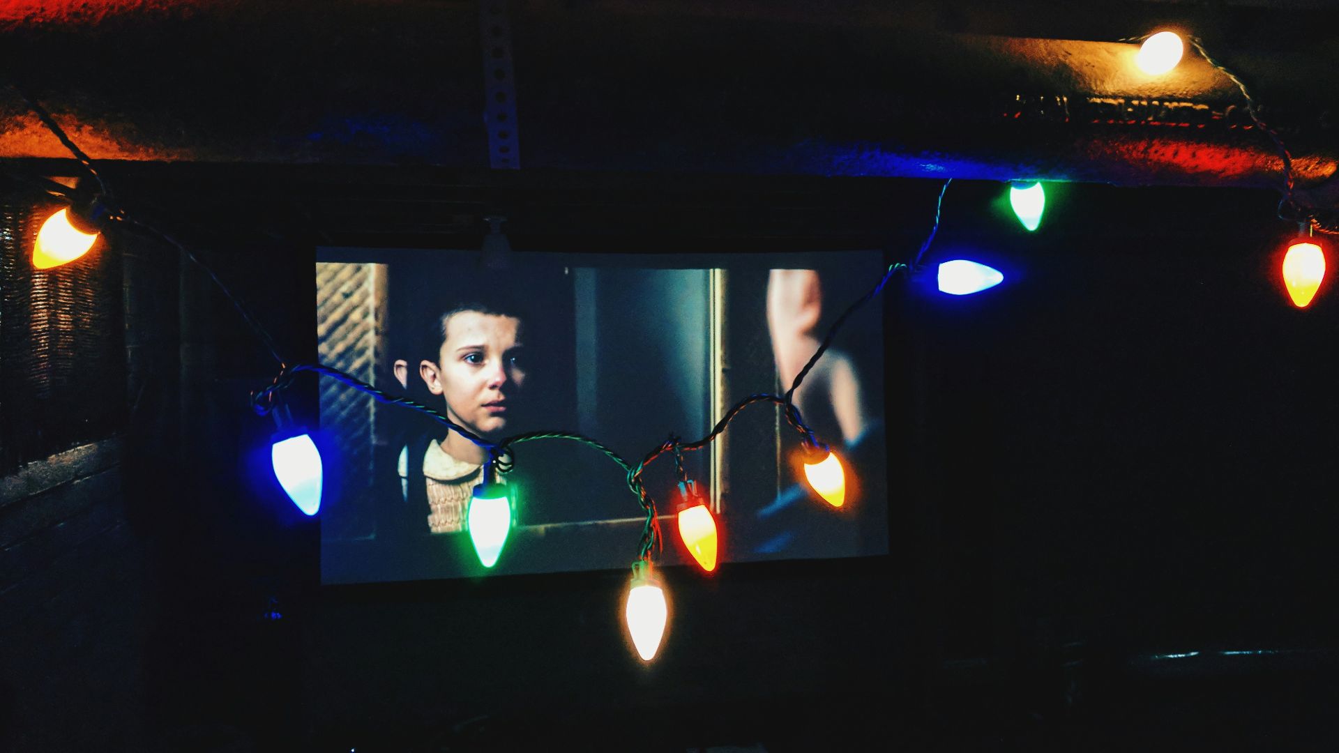 flat screen television near string lights