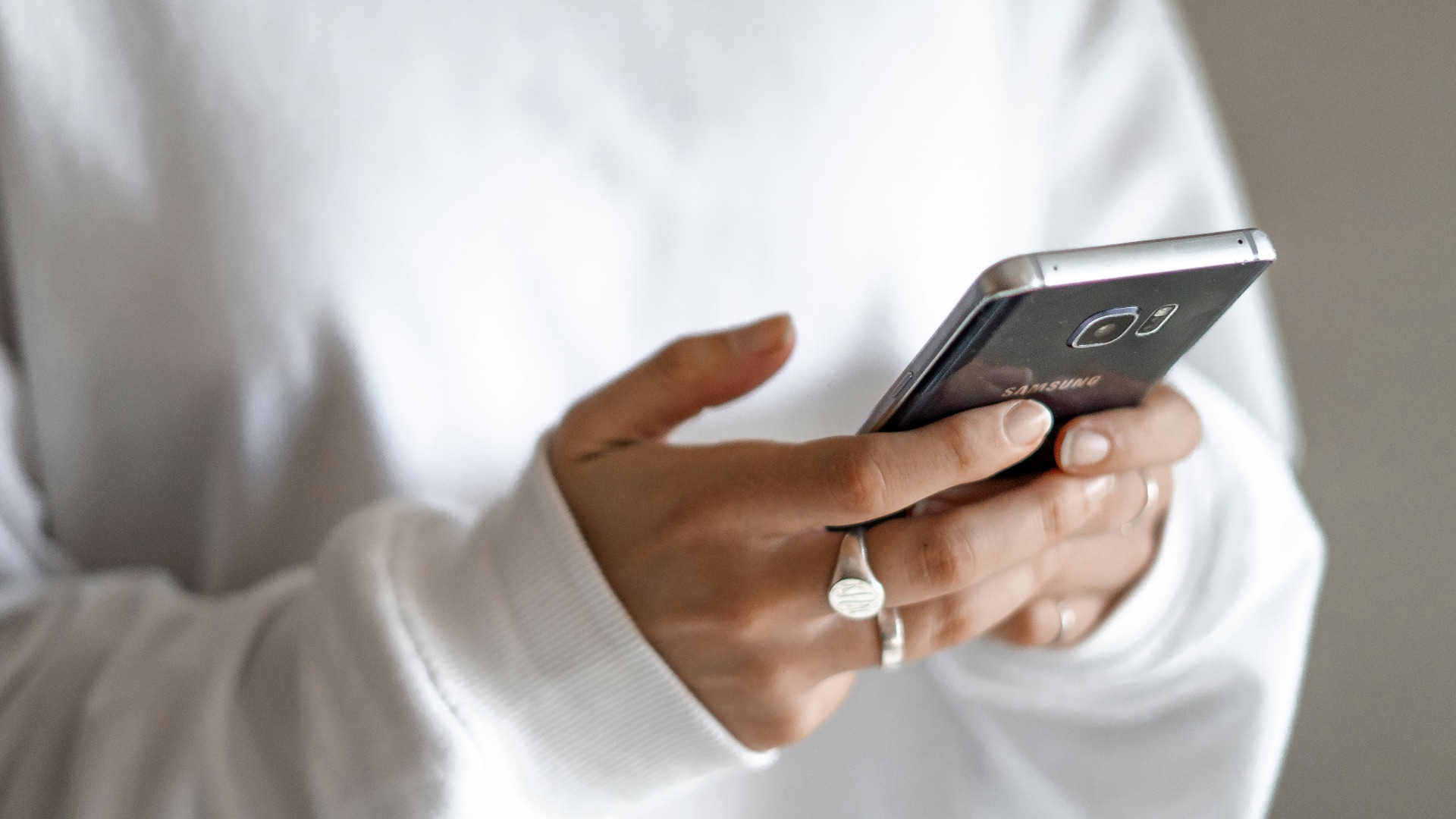 person in white long sleeve shirt holding black smartphone