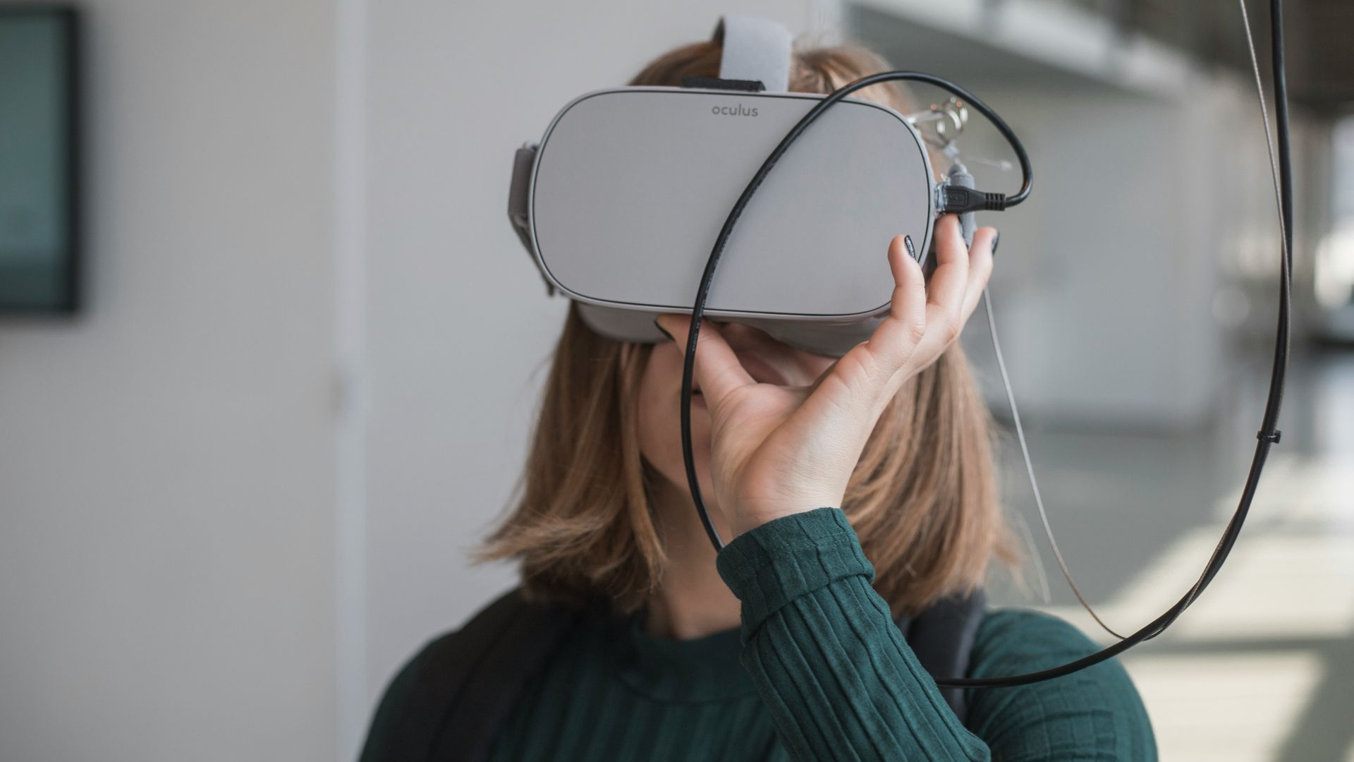woman in black sweater holding white and black vr goggles