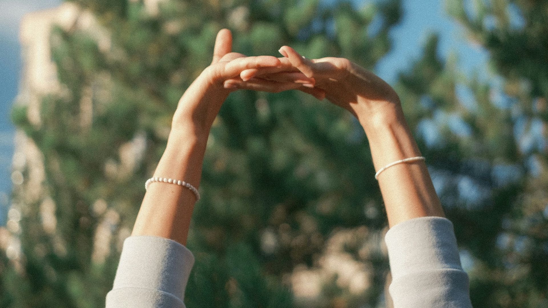 a person reaching up into the air to catch a frisbee