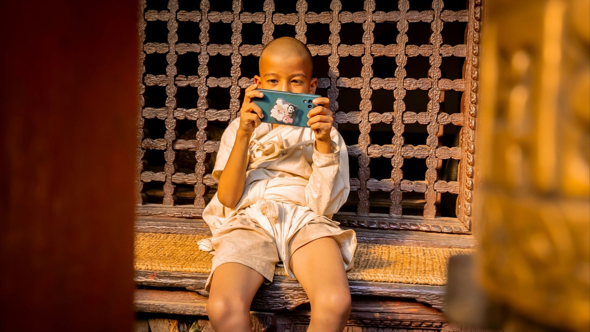 Young monk taking a picture with a camera.
