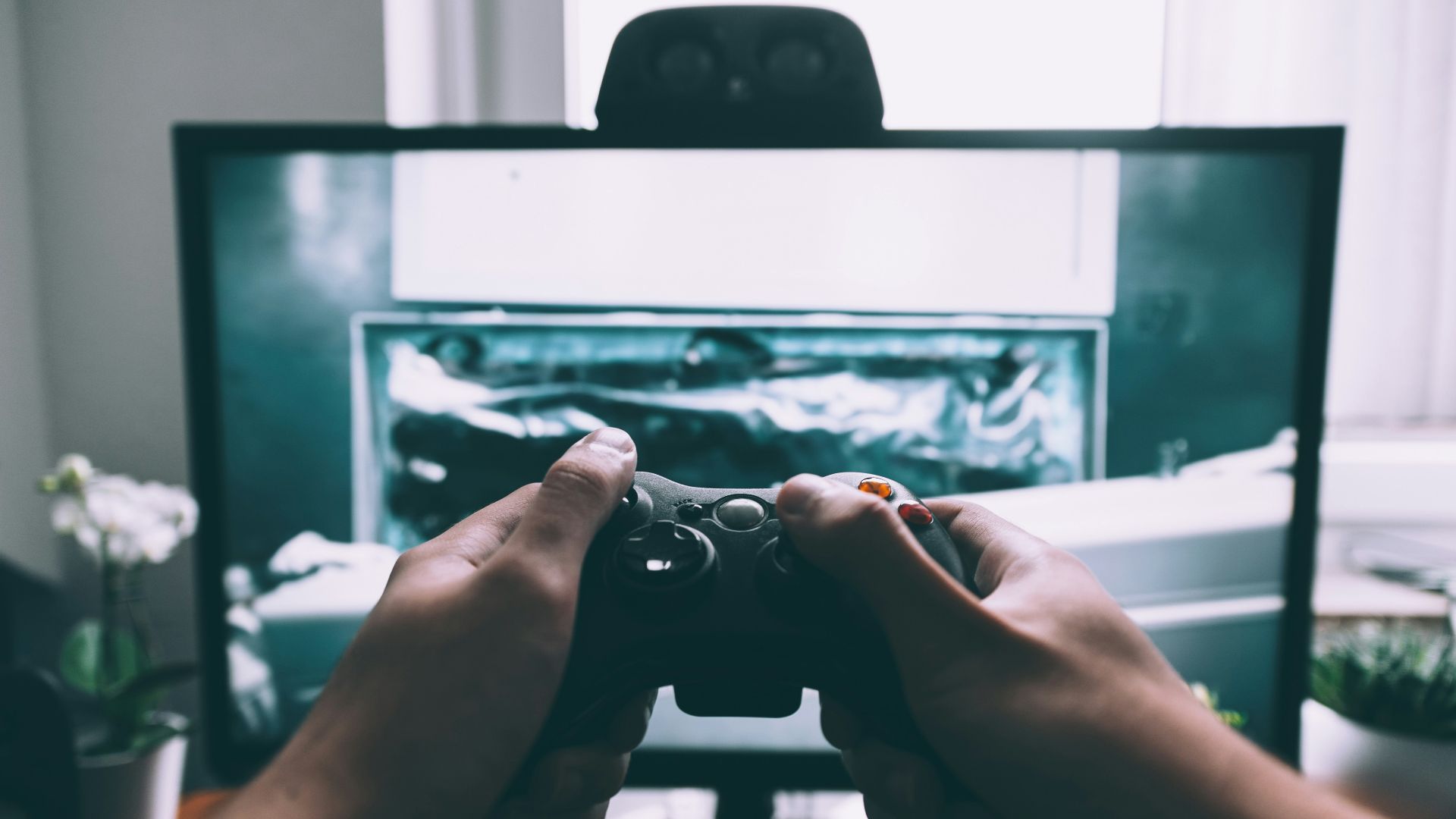 person holding game controller in-front of television