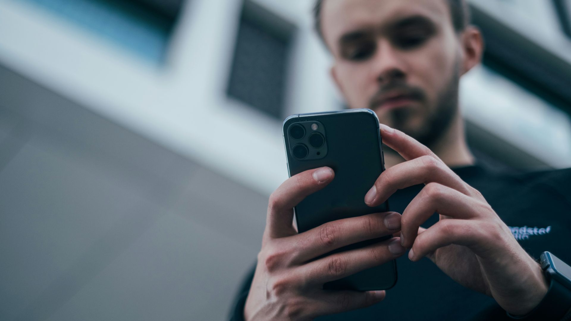 man wearing black sweater using smartphone