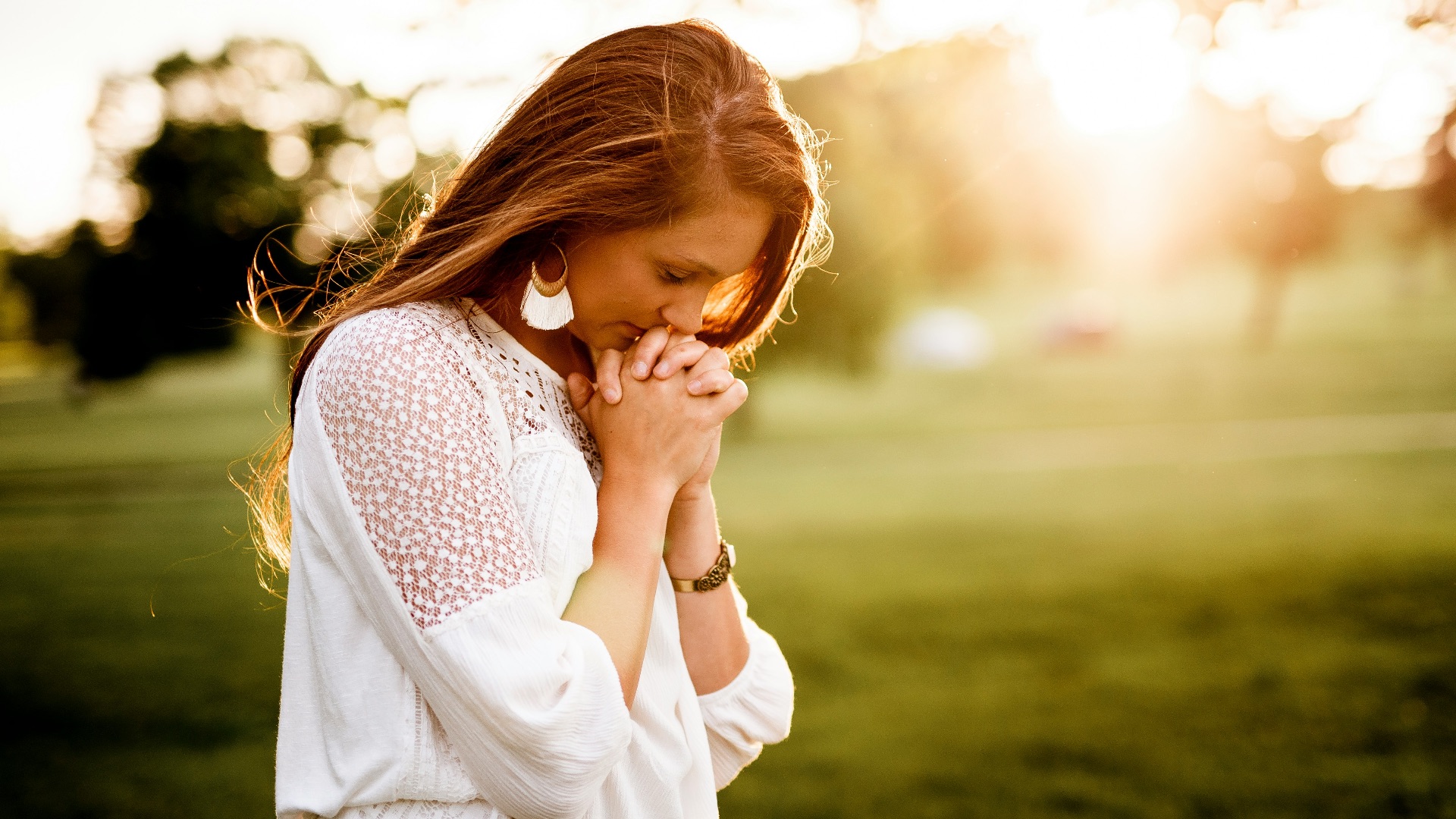 woman praying beside tree