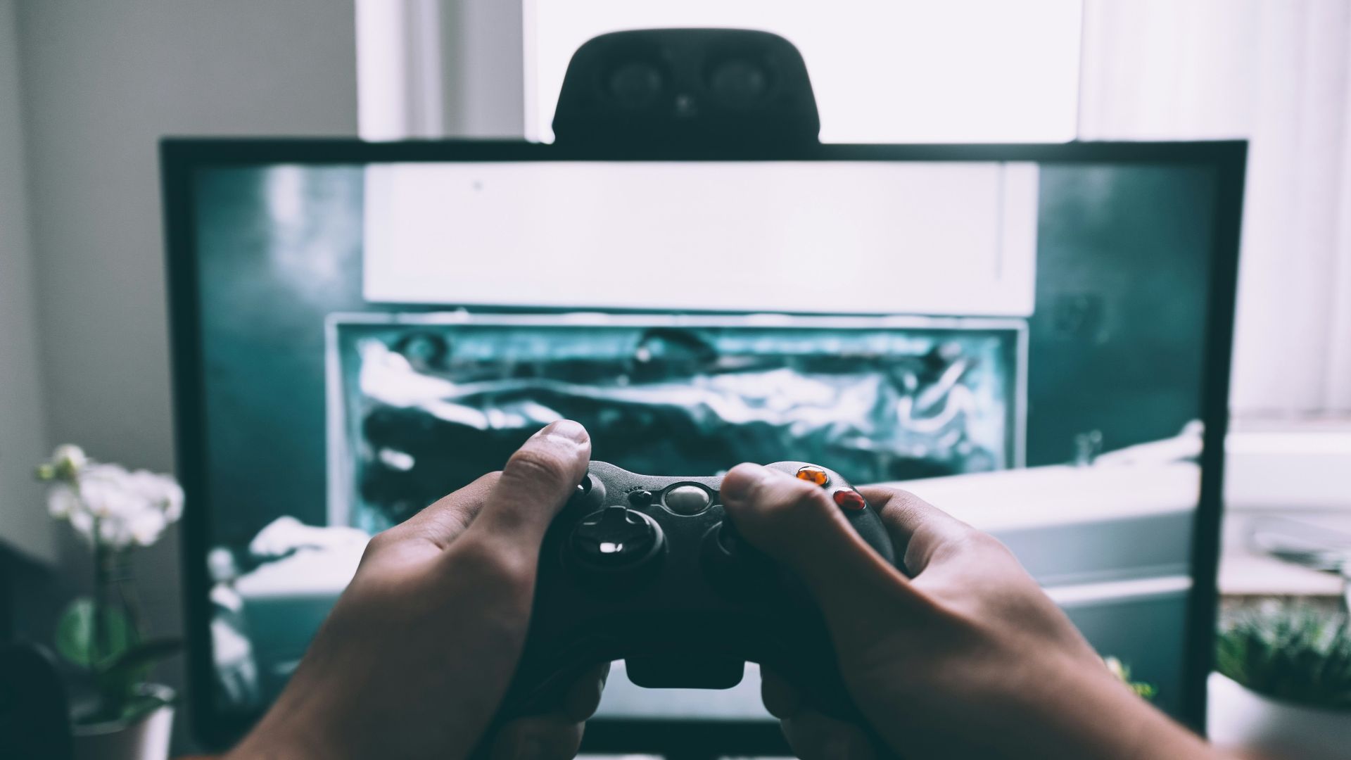 person holding game controller in-front of television