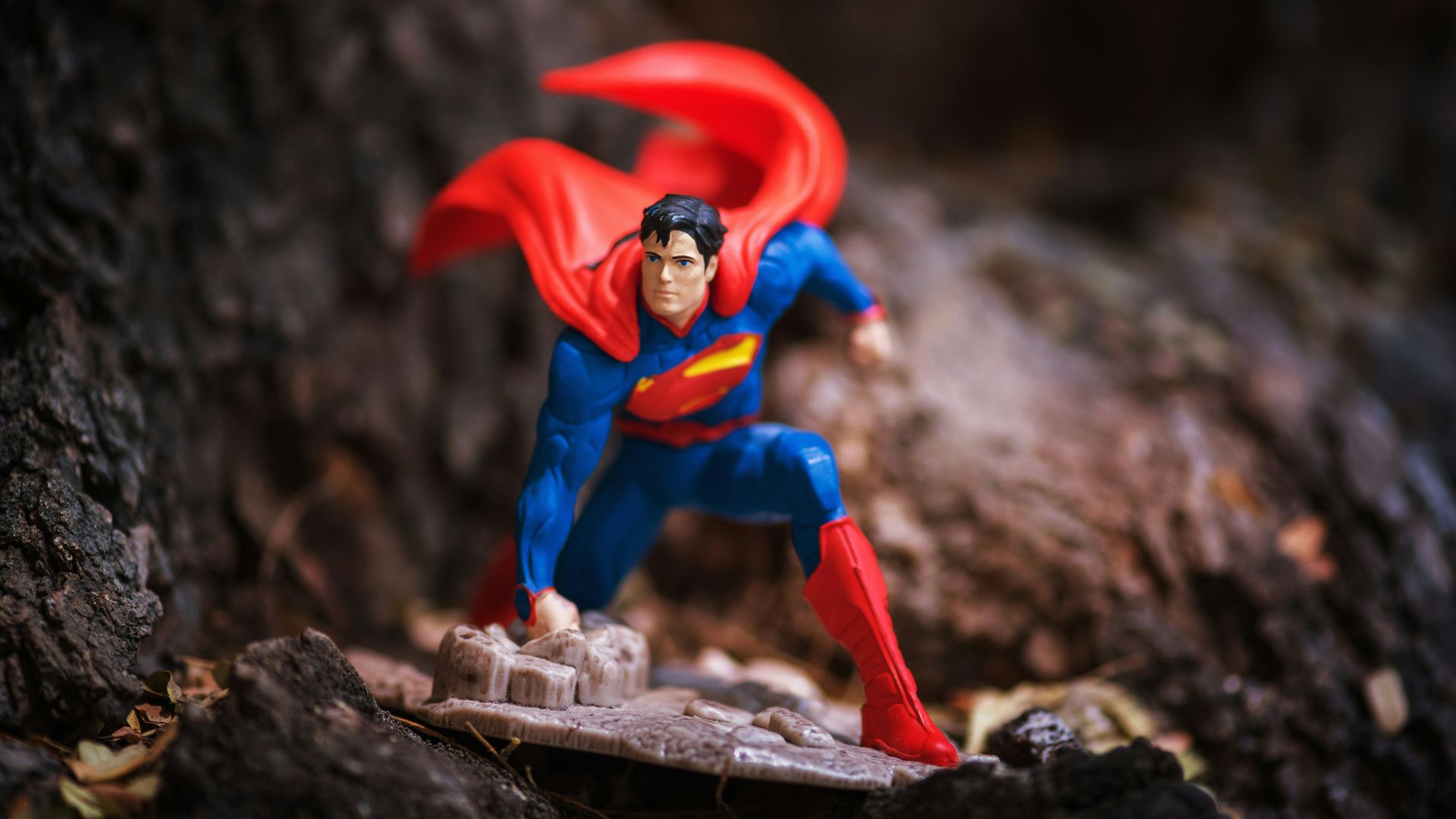 a superman action figure is posed on a rock