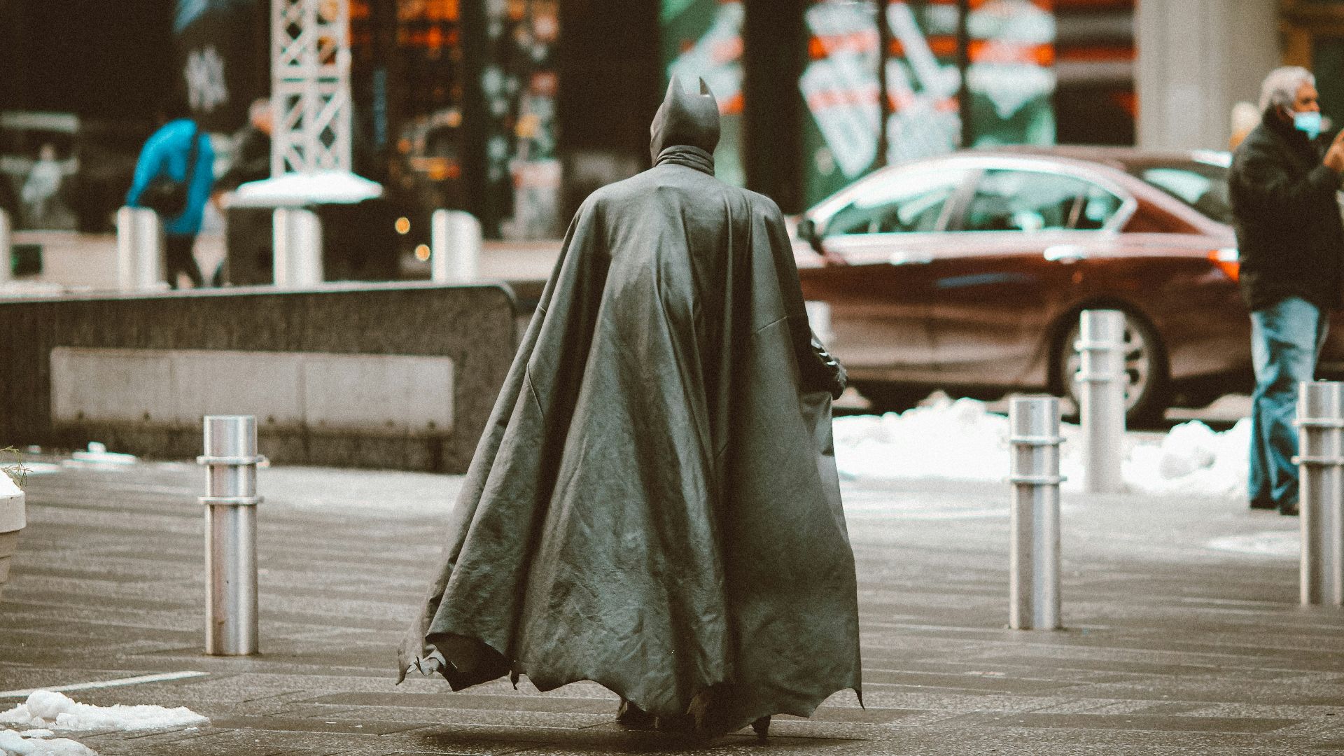 person in gray robe sitting on sidewalk during daytime