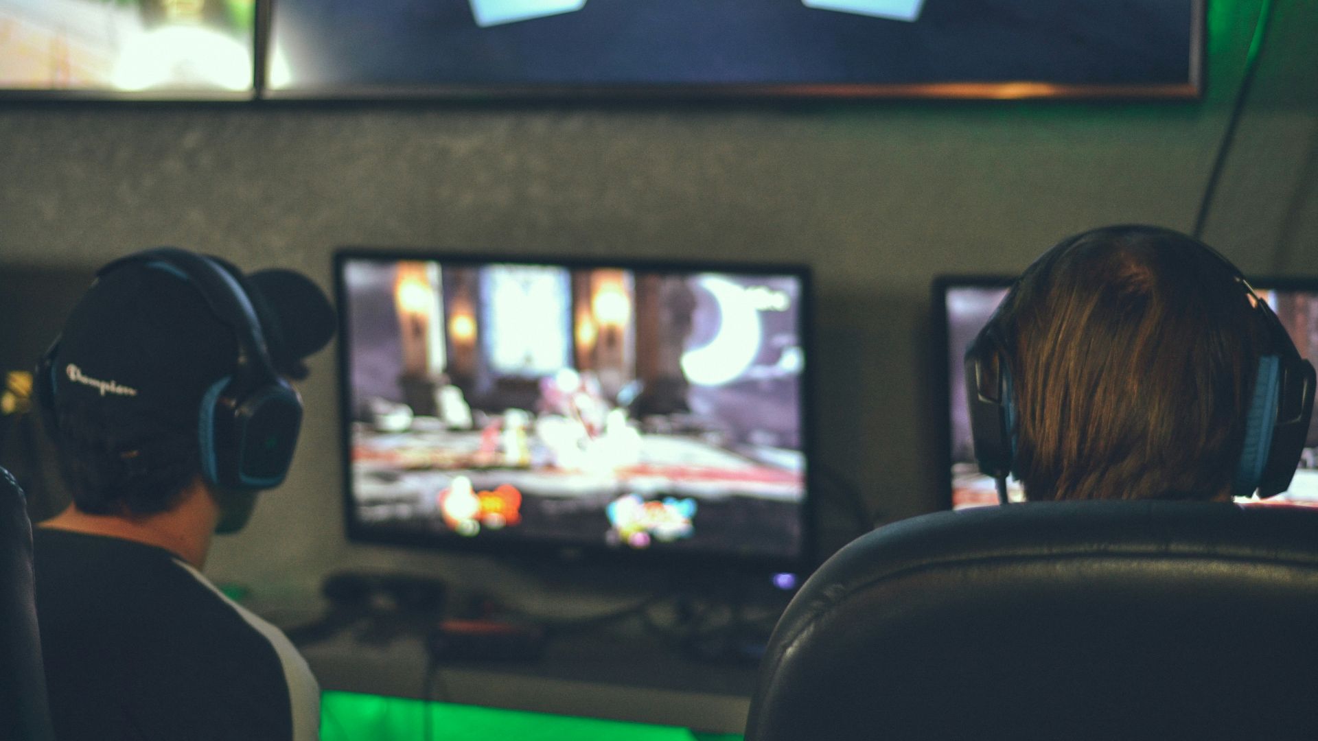 selective focus photography of two persons playing game in front of monitors