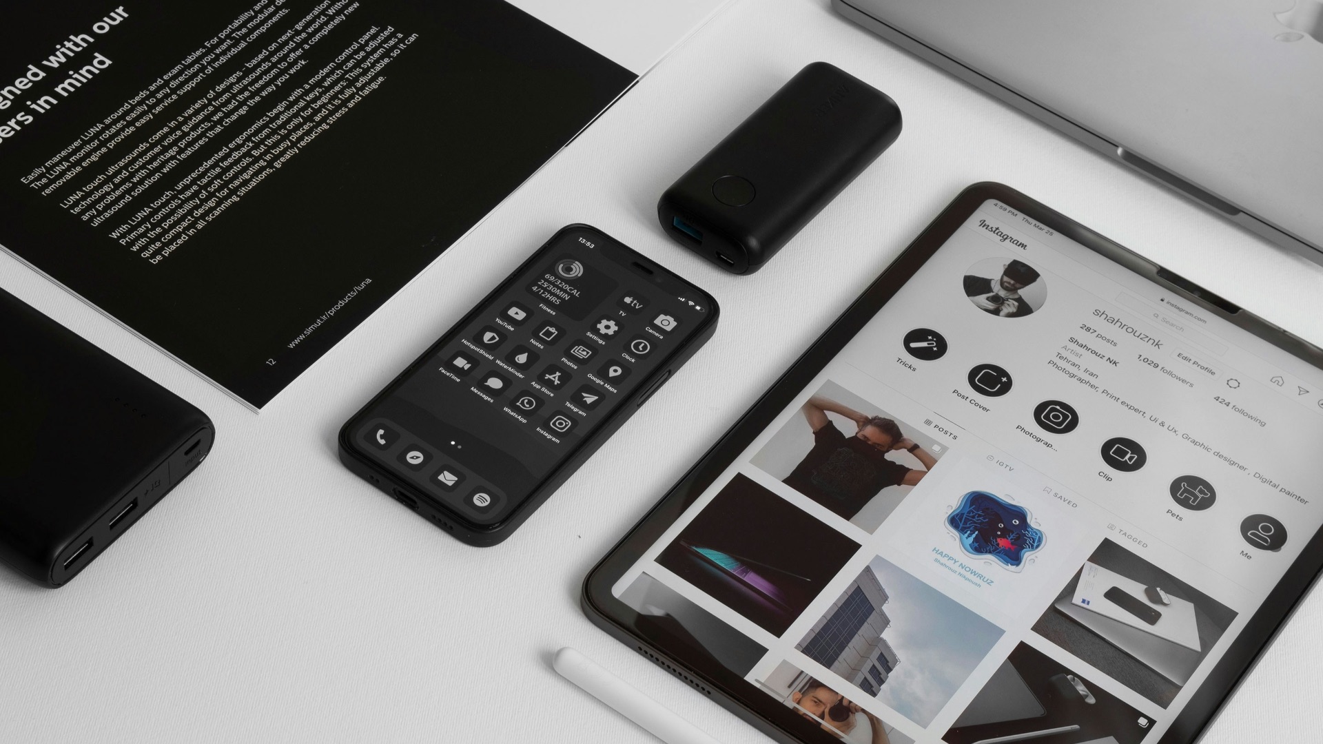 a tablet, keyboard, mouse, cell phone, and other electronics on a table