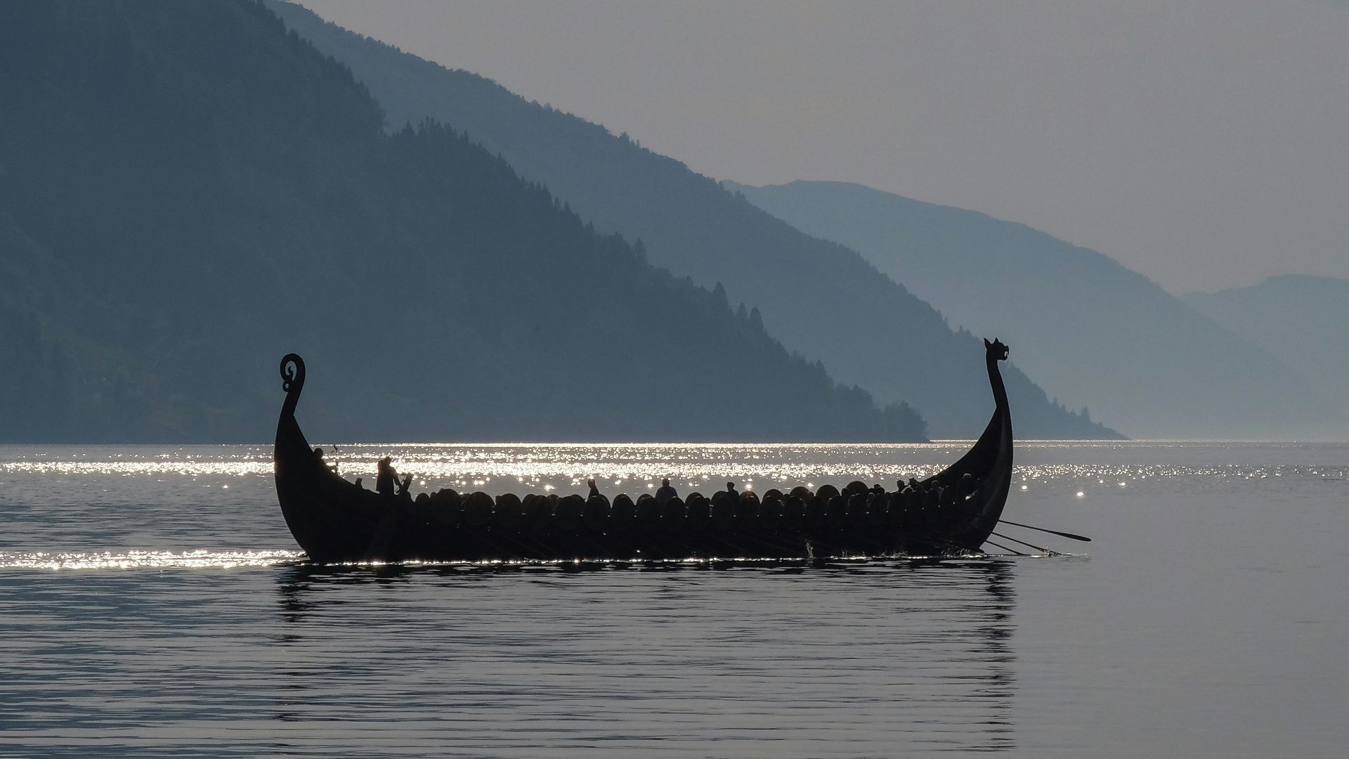 a long boat with two people in it on a lake