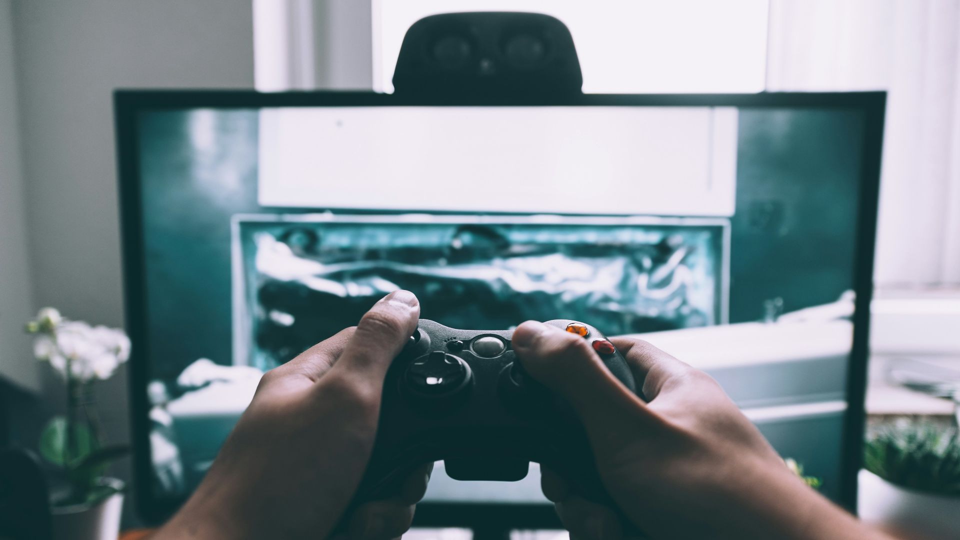 person holding game controller in-front of television
