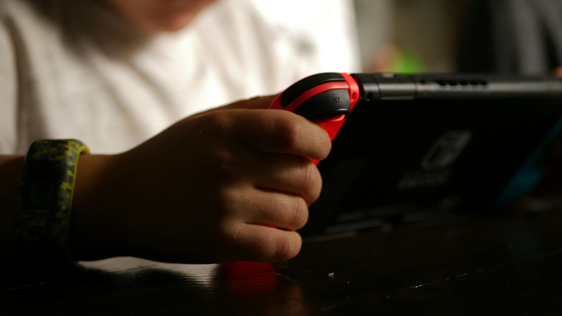 boy in white crew neck t-shirt holding black and red cordless device