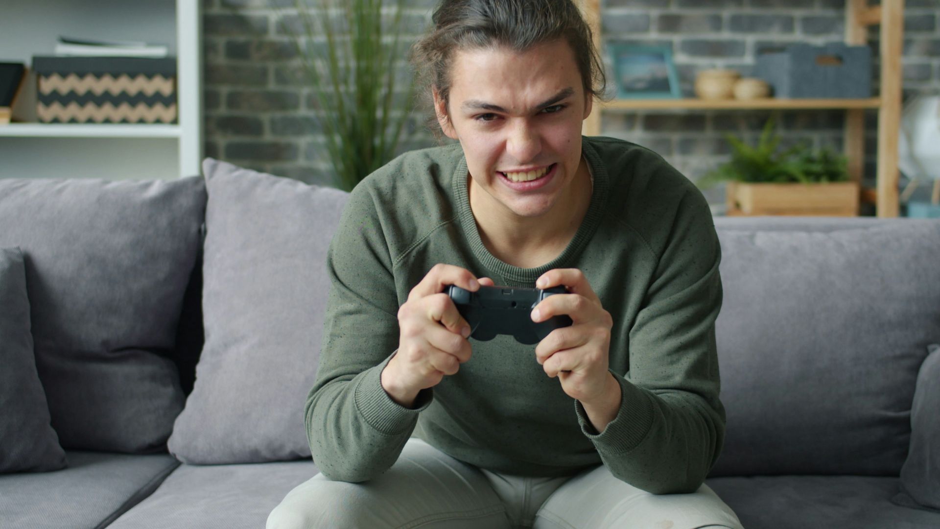 Young man intensely playing video games on couch
