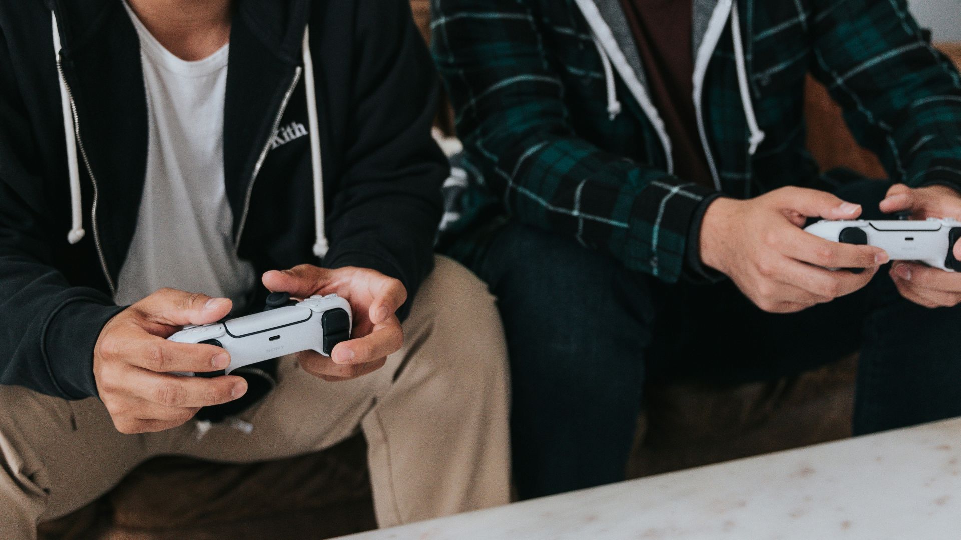 a couple of men sitting at a table with game controllers