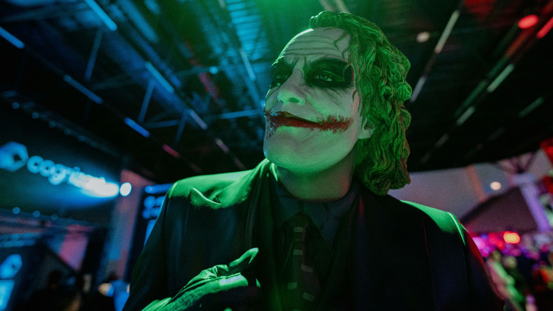 The joker smiles in the green and blue light.