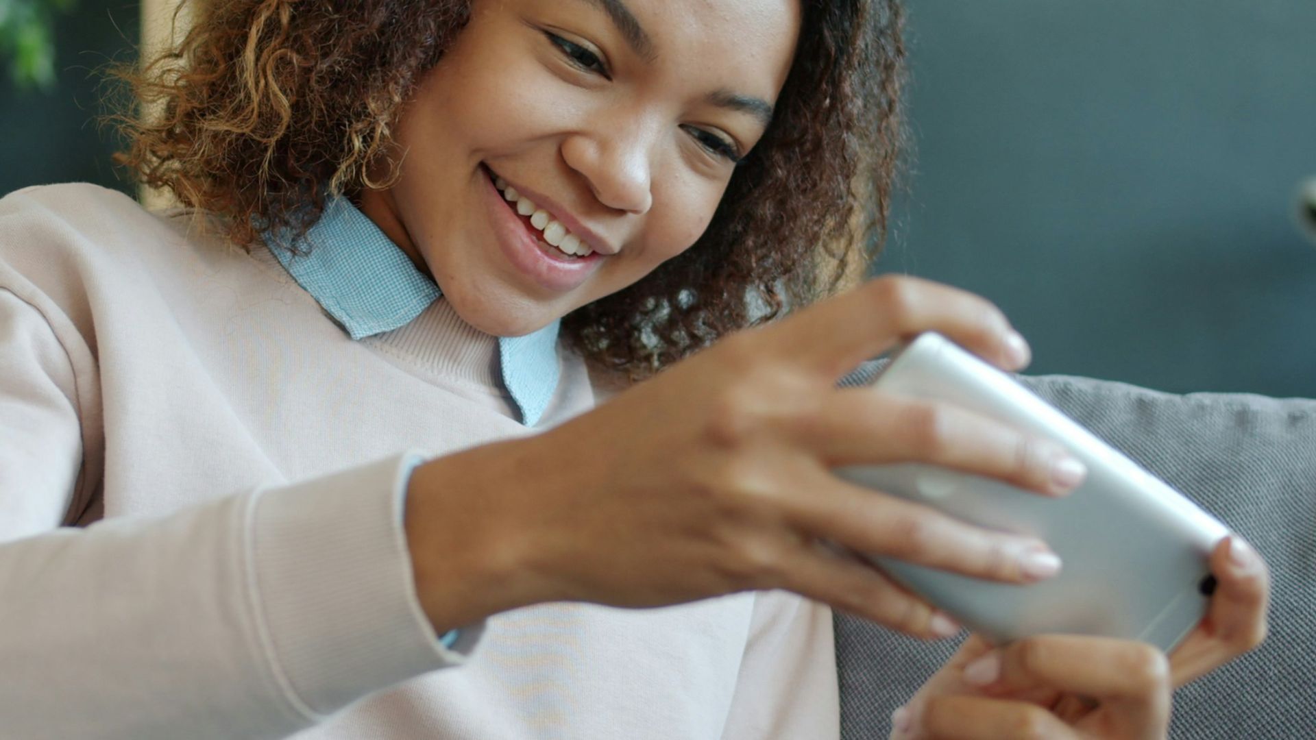 Young woman smiling while playing on her phone
