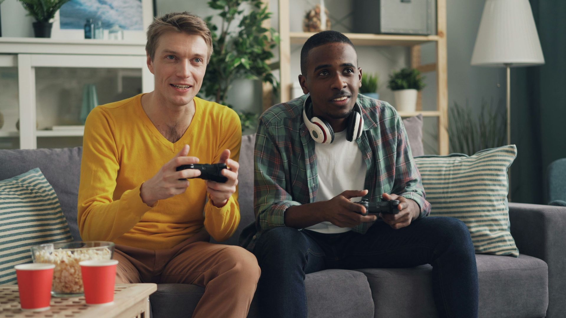 two men sitting on a couch playing video games