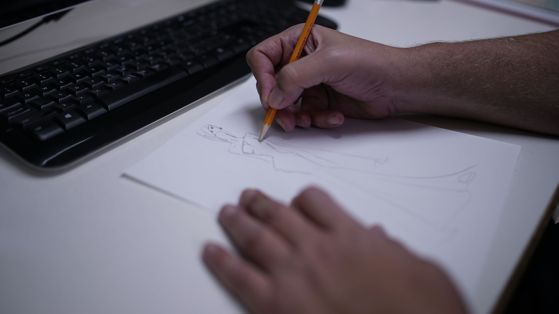 a person drawing on a piece of paper with a pencil
