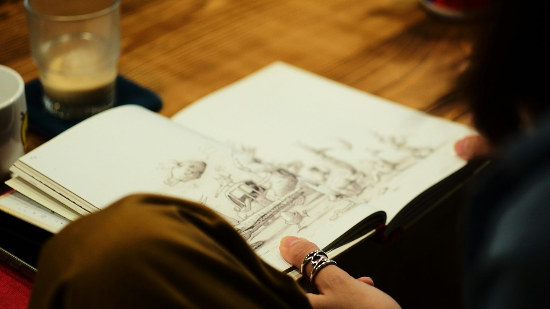 Someone is sketching in a notebook with coffee nearby.