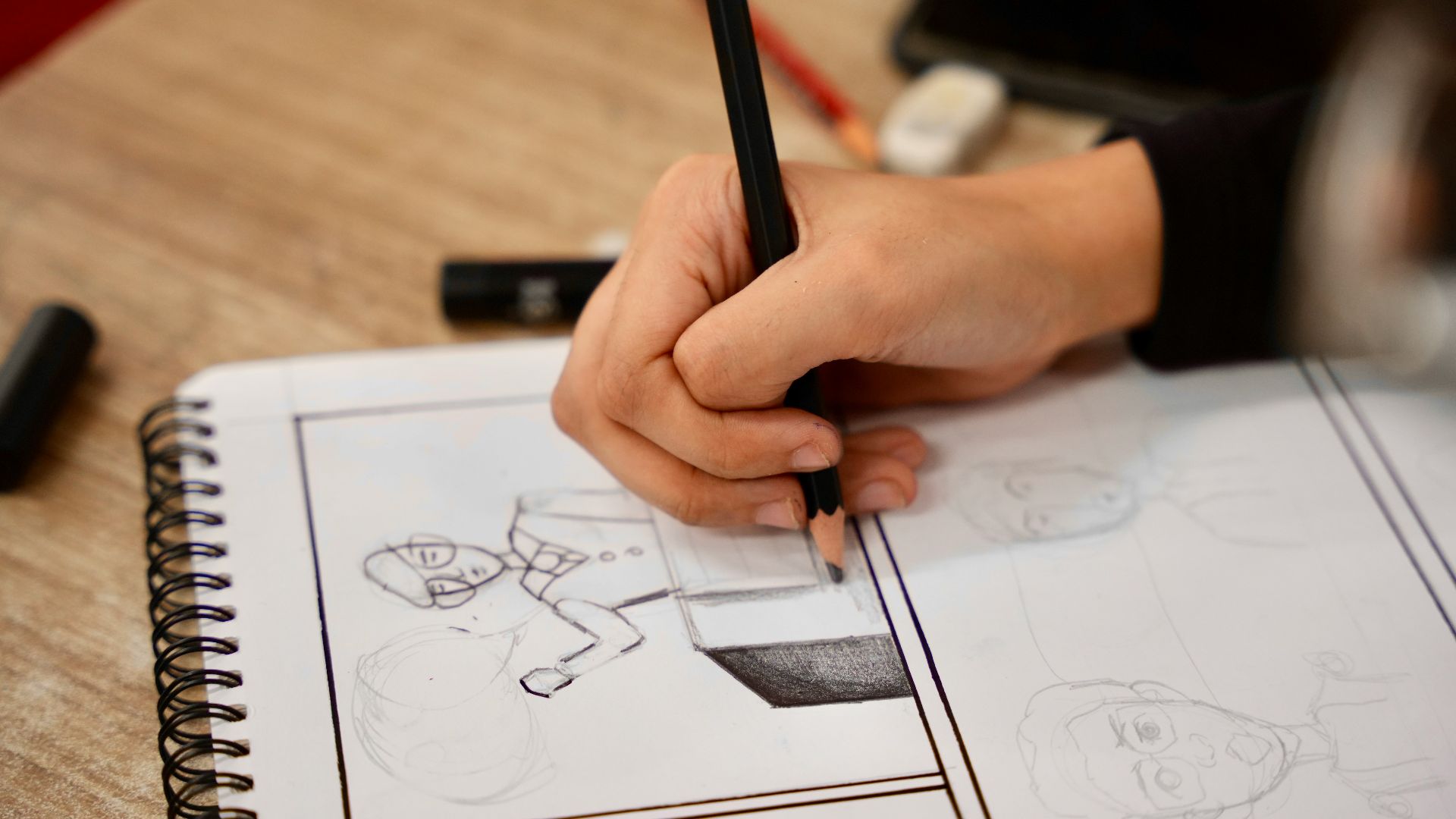 A person holding a pencil and drawing on a book