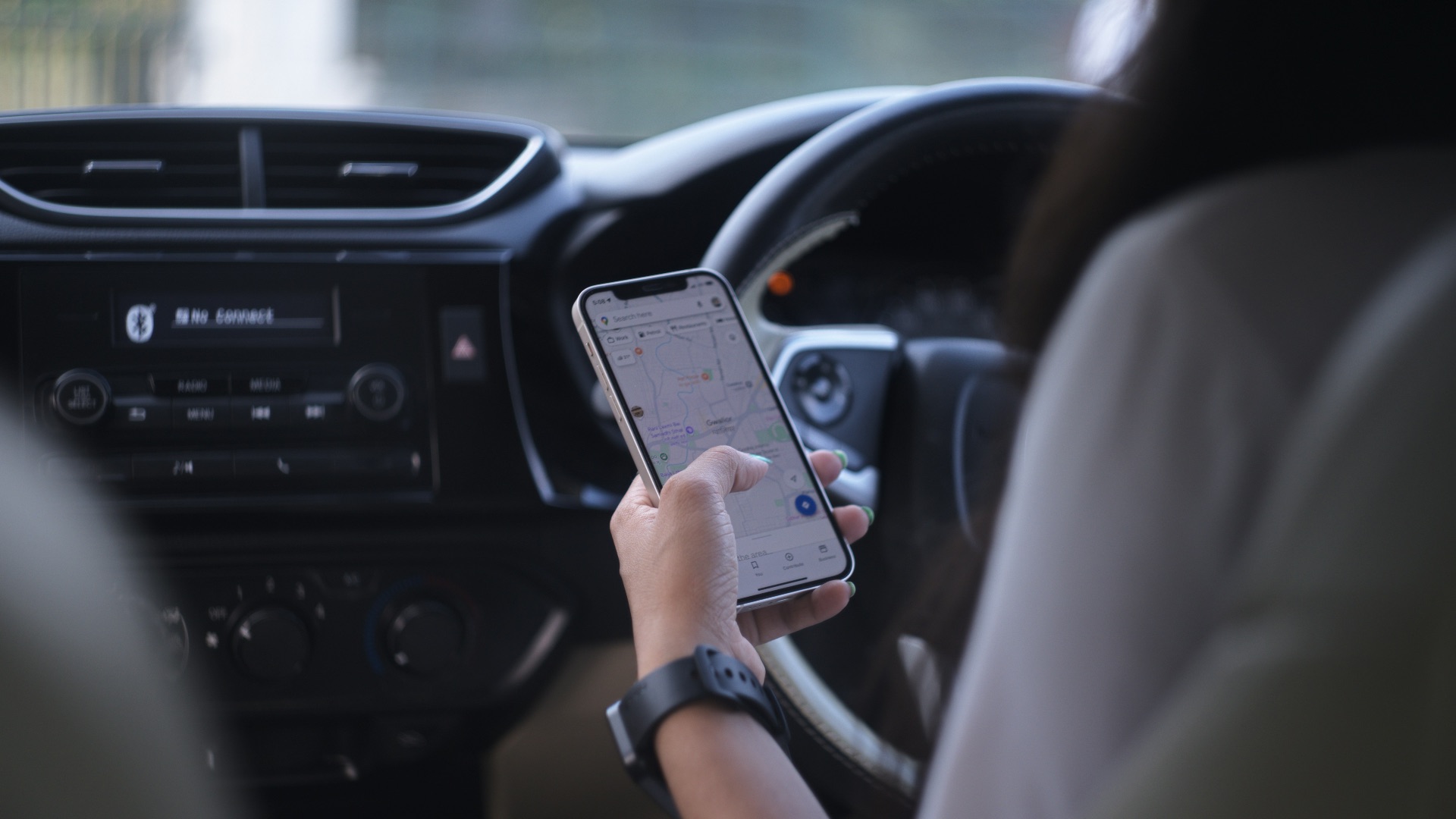 A woman holding a cell phone while driving a car