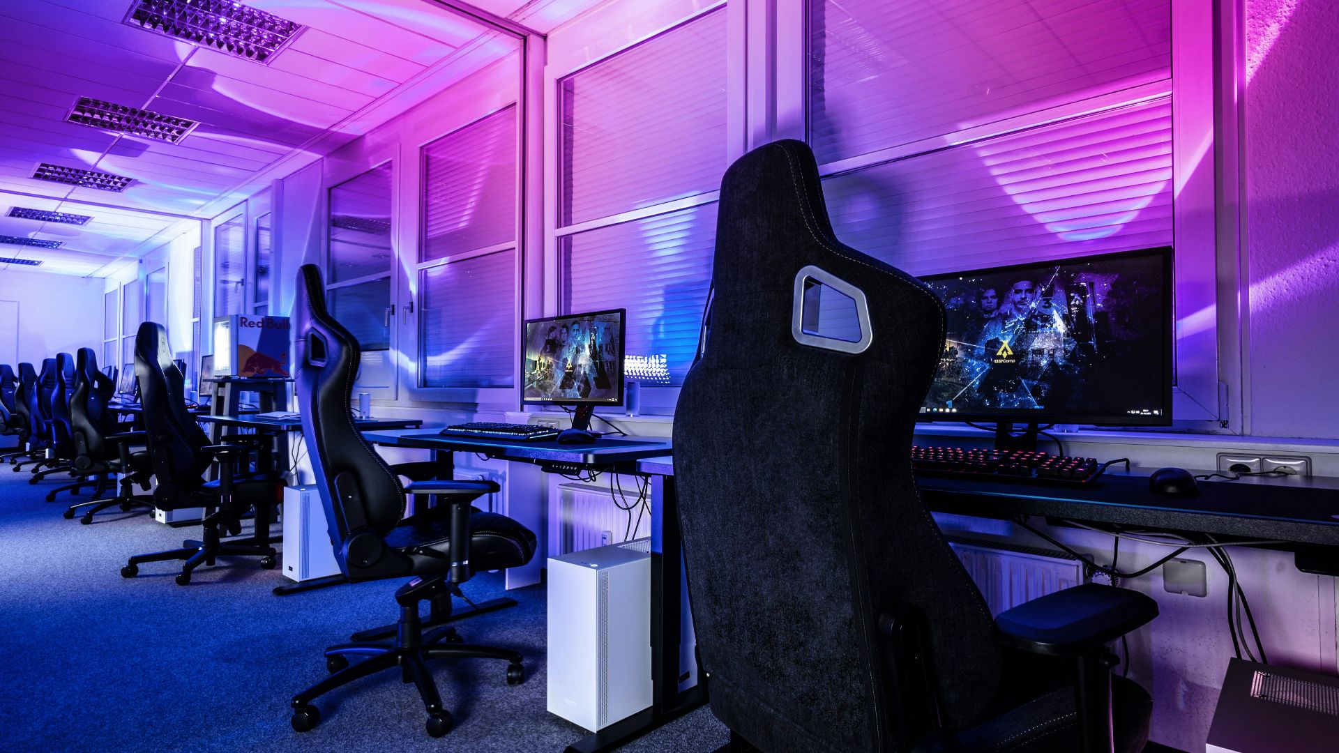 a room filled with lots of computer desks and chairs