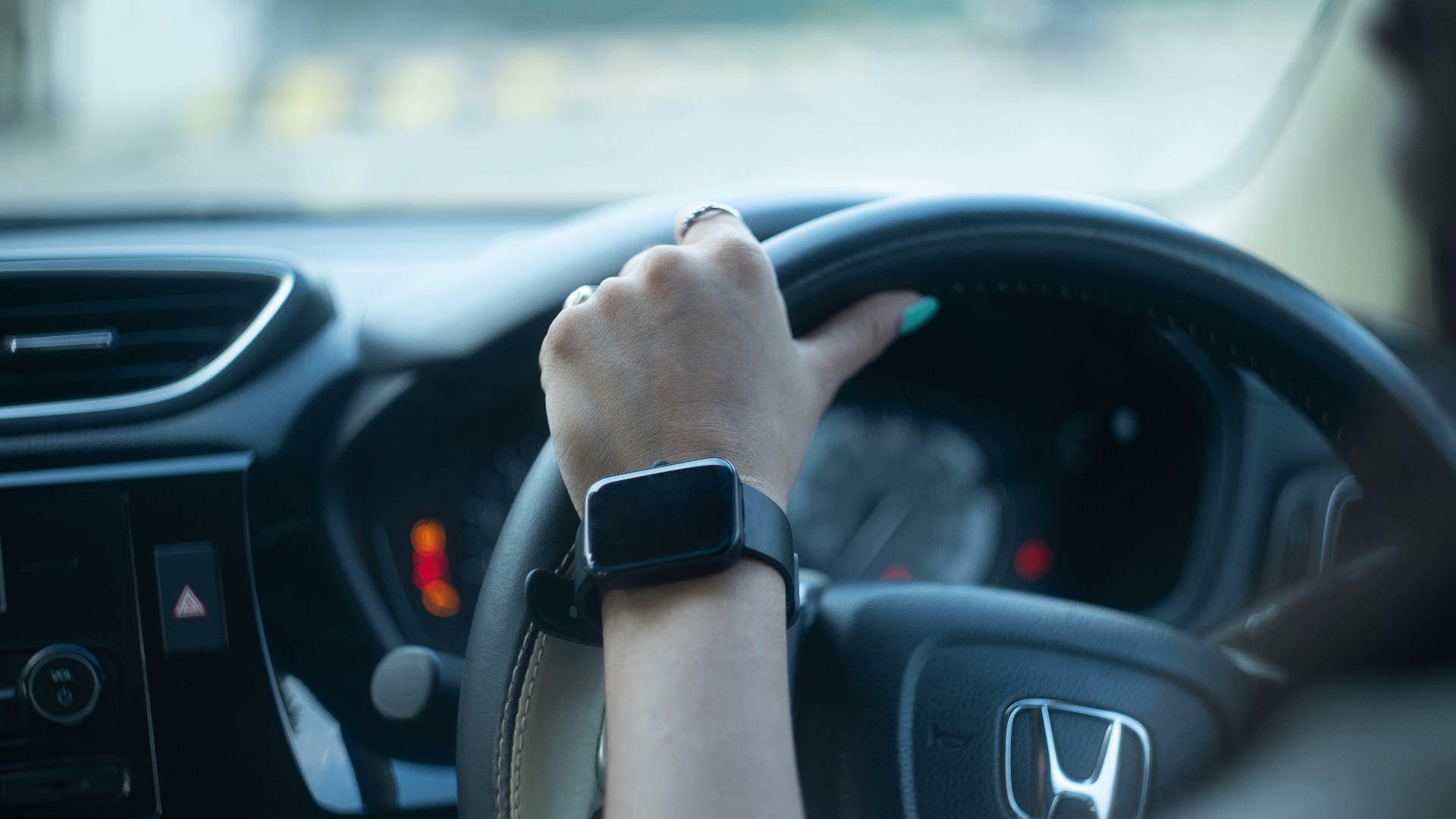 A woman driving a car with her hand on the steering wheel