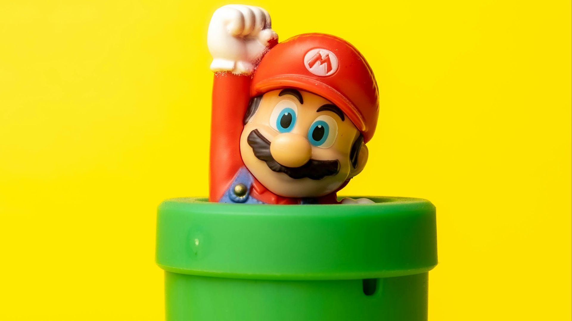 a toy mario in a green container on a yellow background