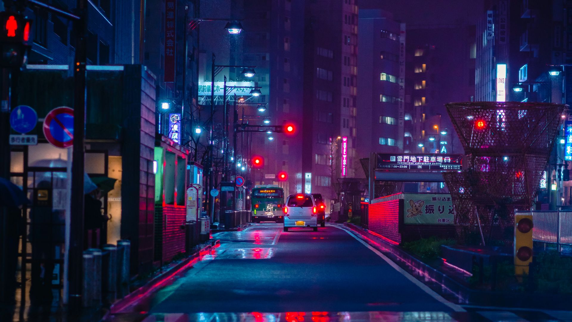 cars on road between high rise buildings during night time