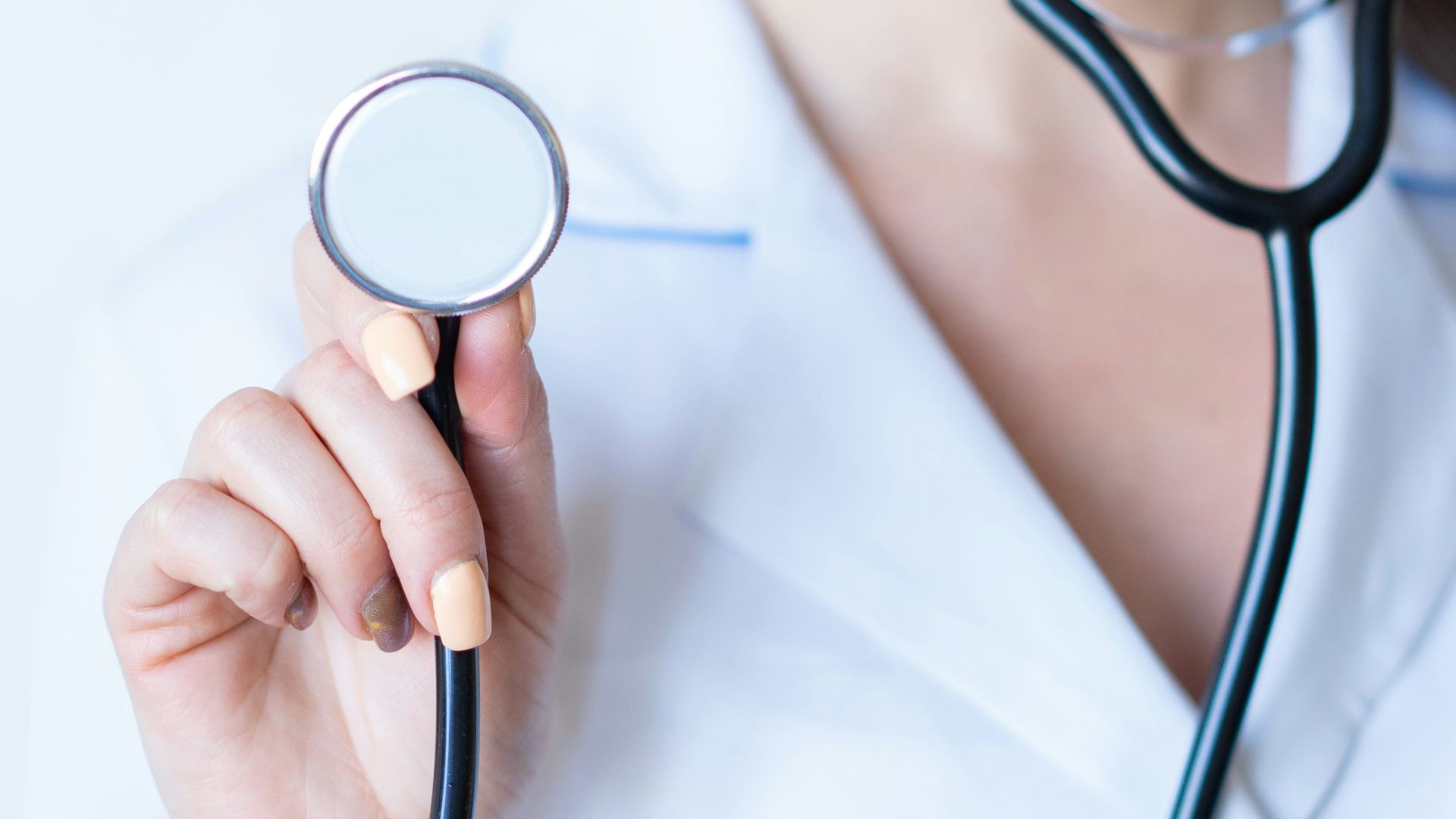 a woman in a white shirt holding a stethoscope