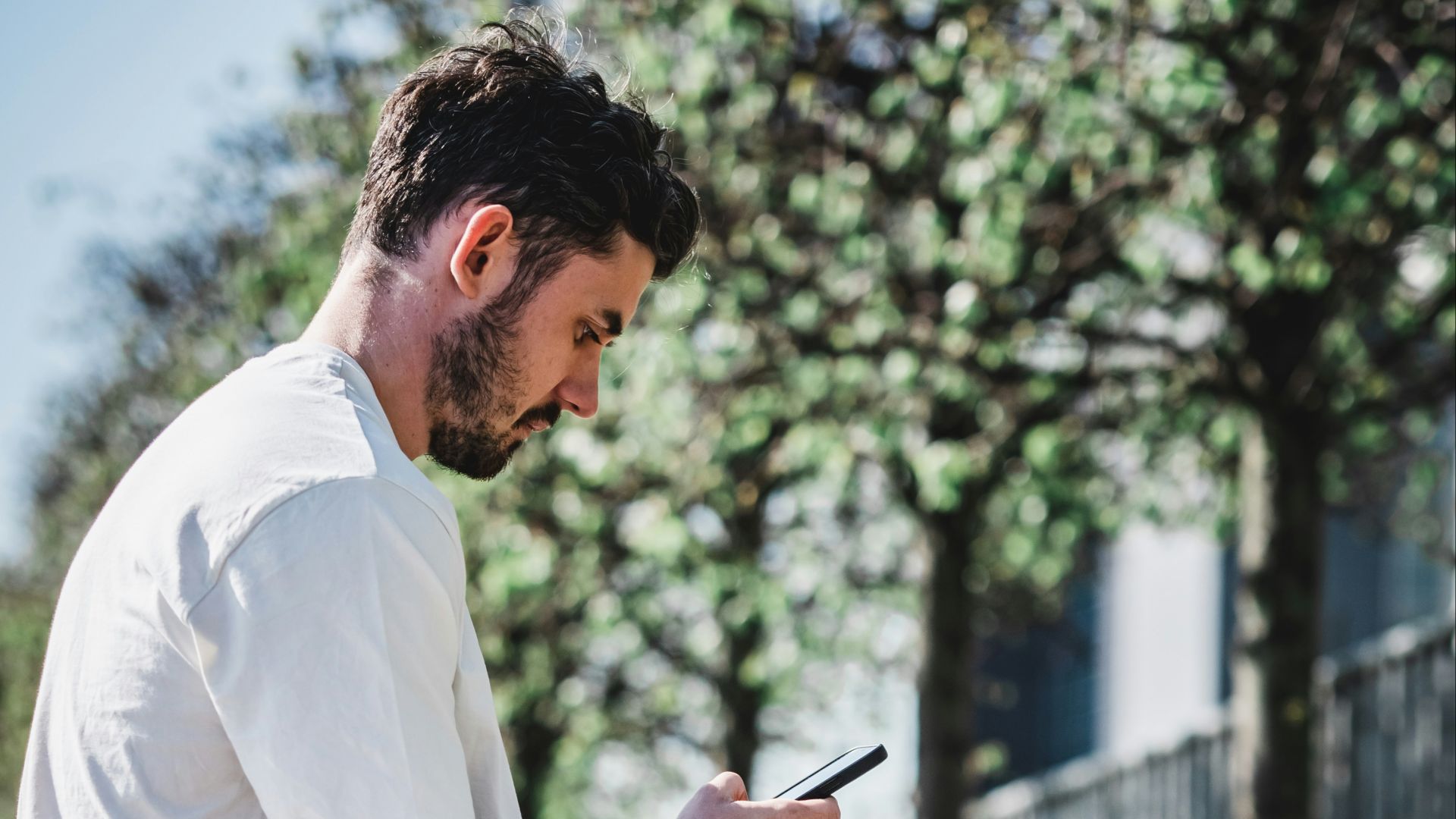 man in white dress shirt and black shorts sitting on brown concrete bench during daytime