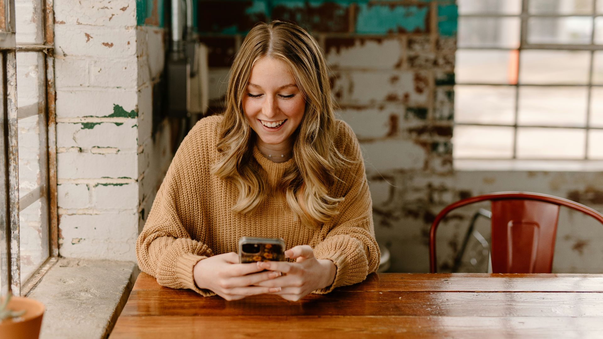 a woman sitting at a table looking at her cell phone