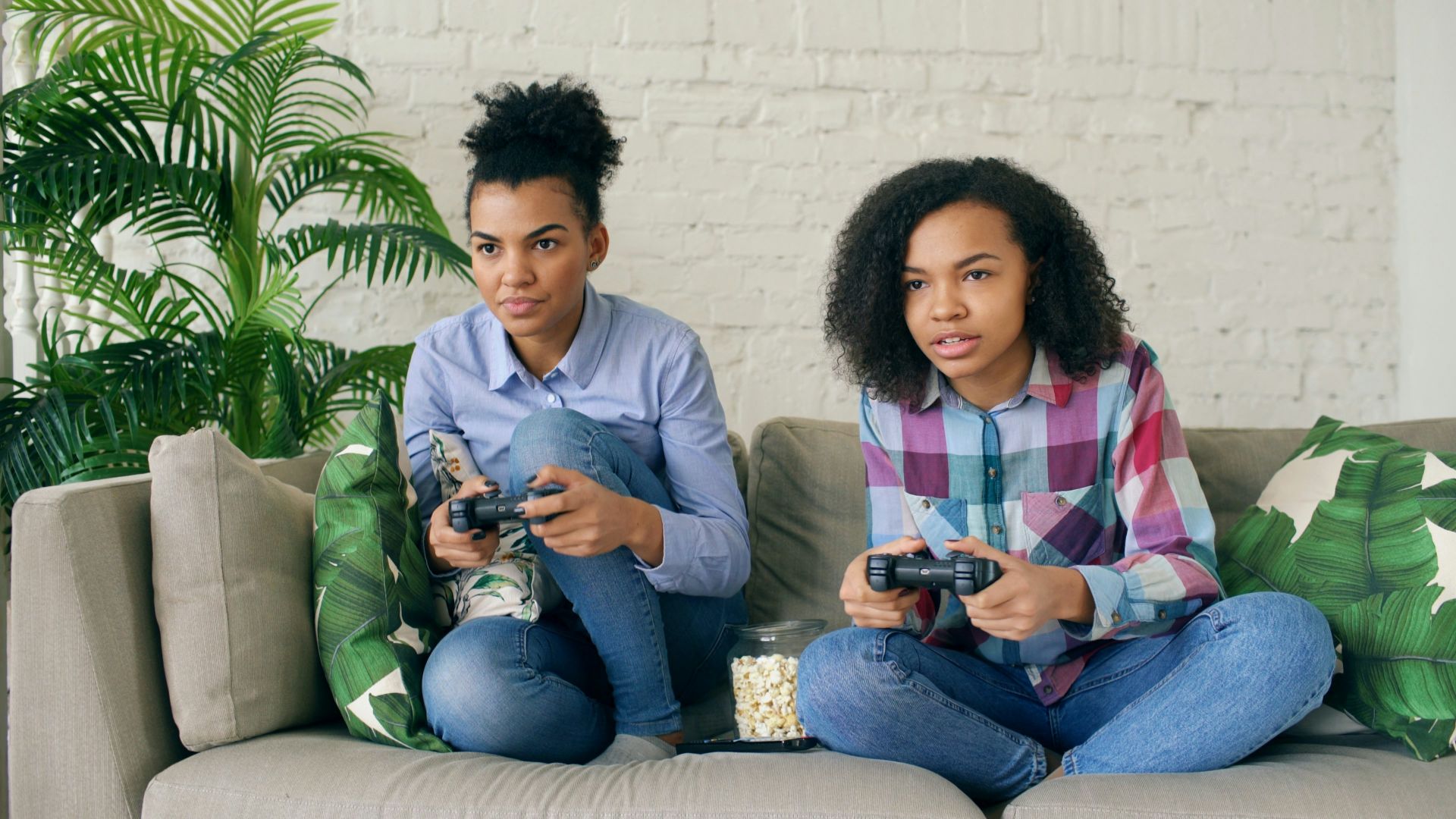 Two women playing video games on a couch.