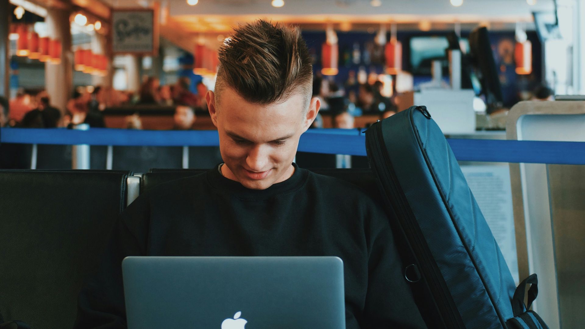 smiling man facing Apple MacBook