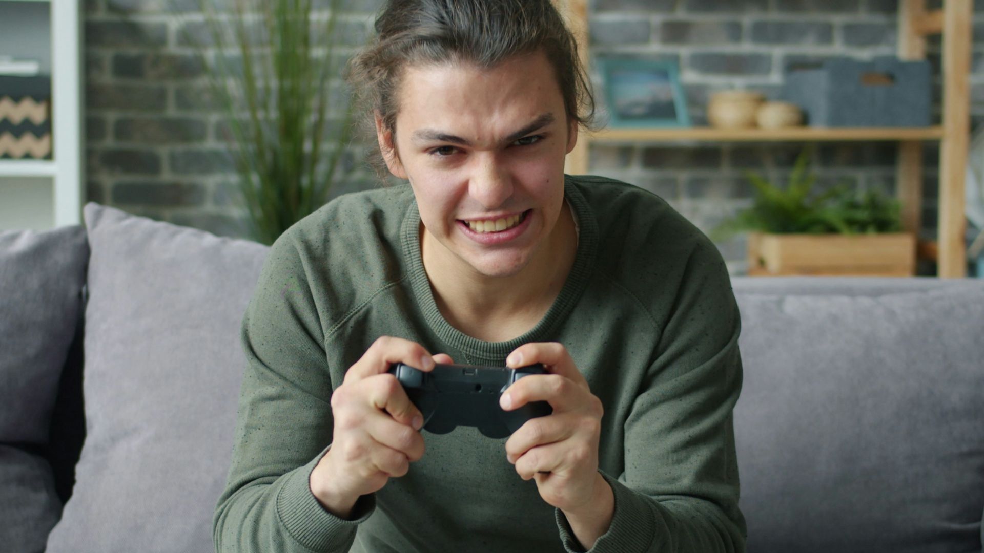 Young man intensely playing video games on couch
