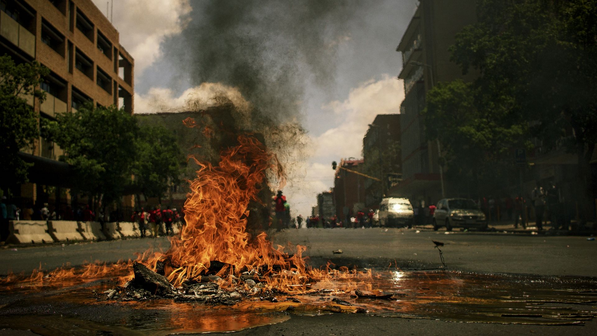 fire burning on the road with high rise buildings during daytime photography