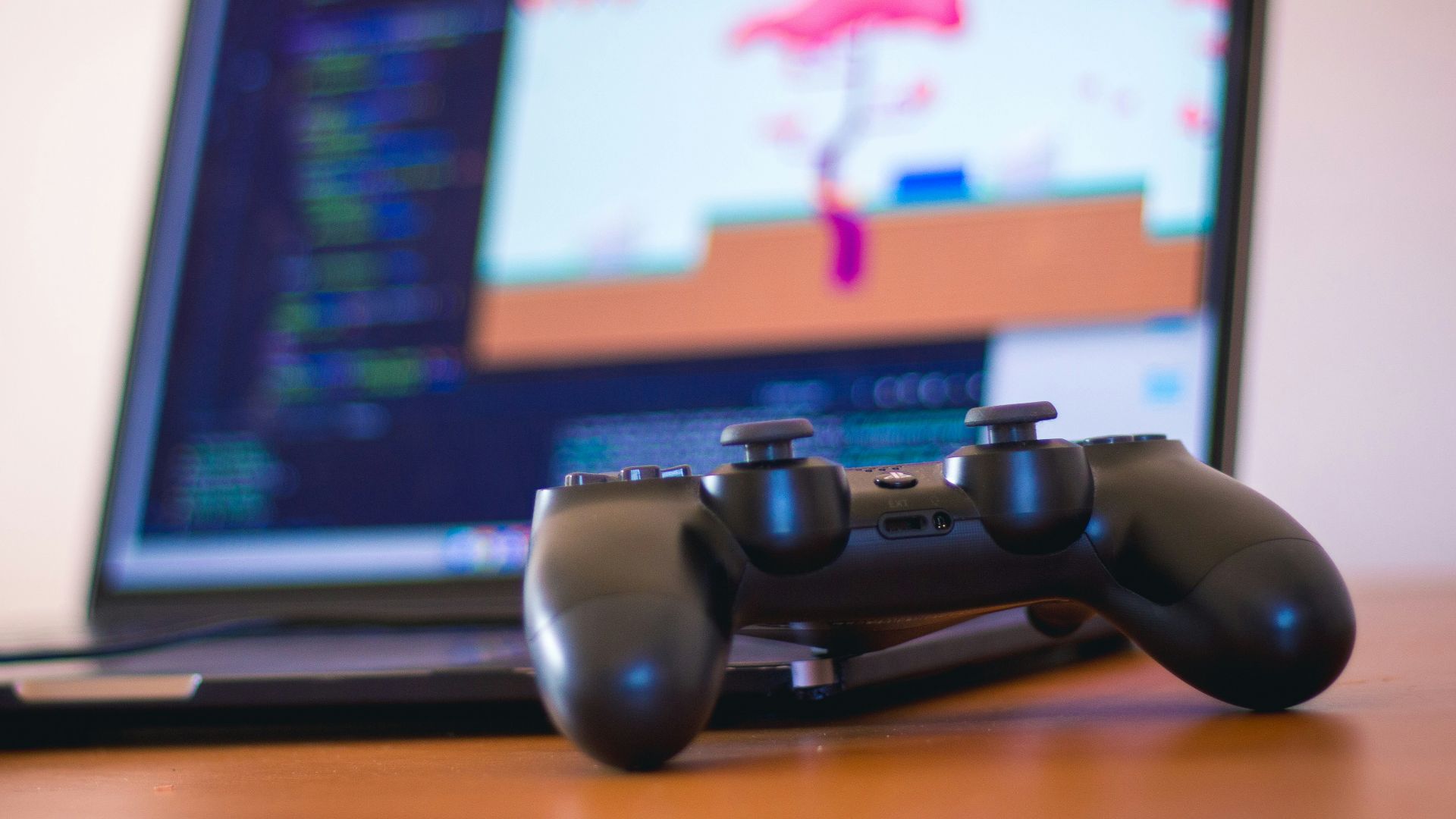 black laptop computer beside controller on brown wooden surface
