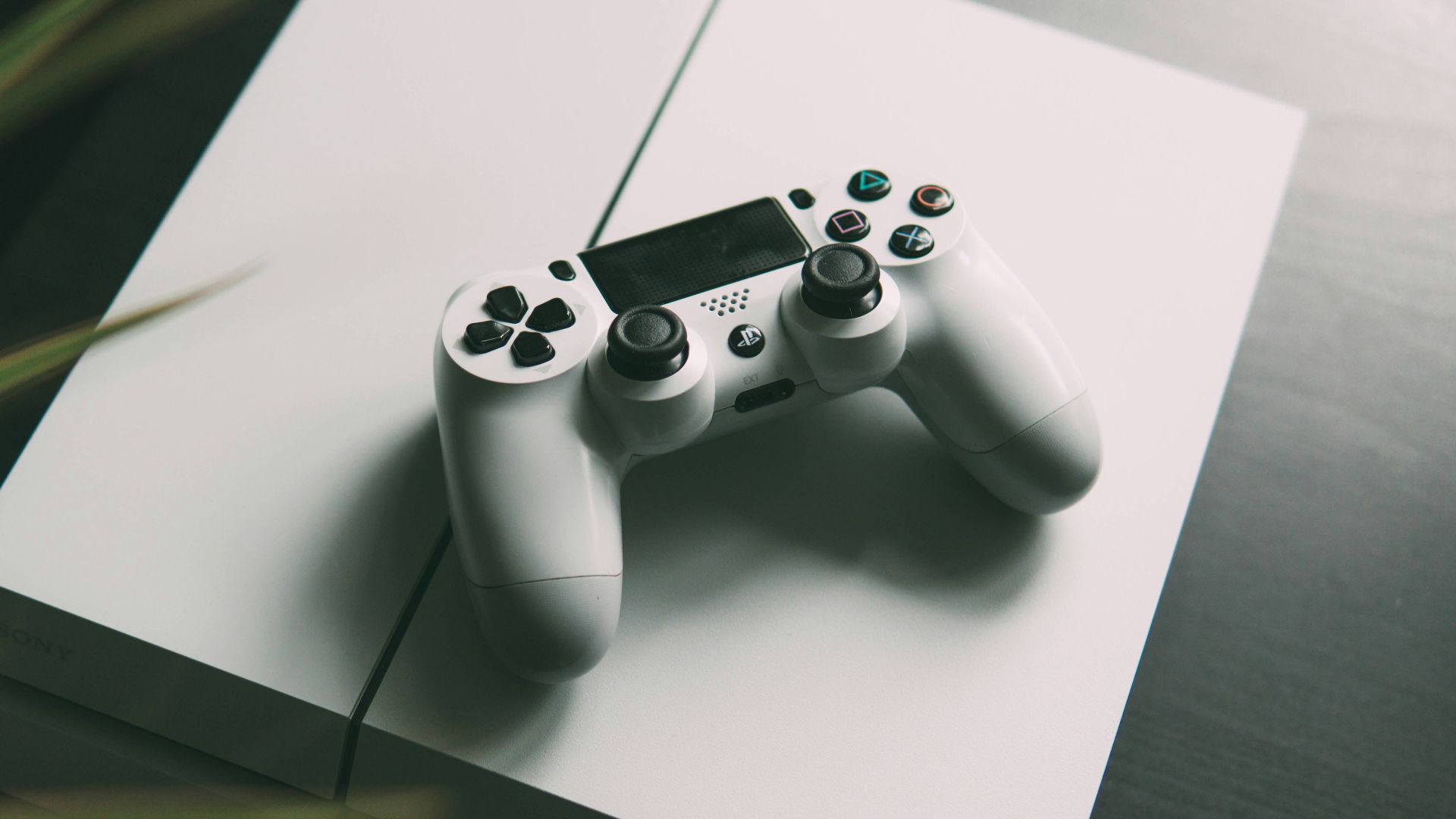 selective focus photography of white Sony PS4 console with wireless controller