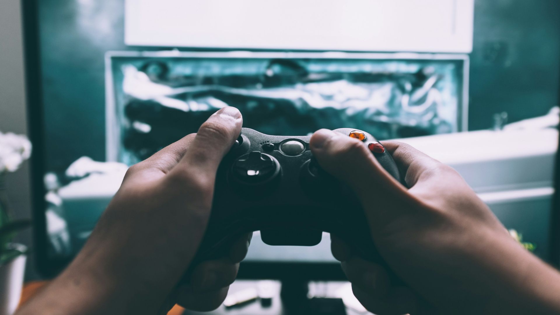 person holding game controller in-front of television