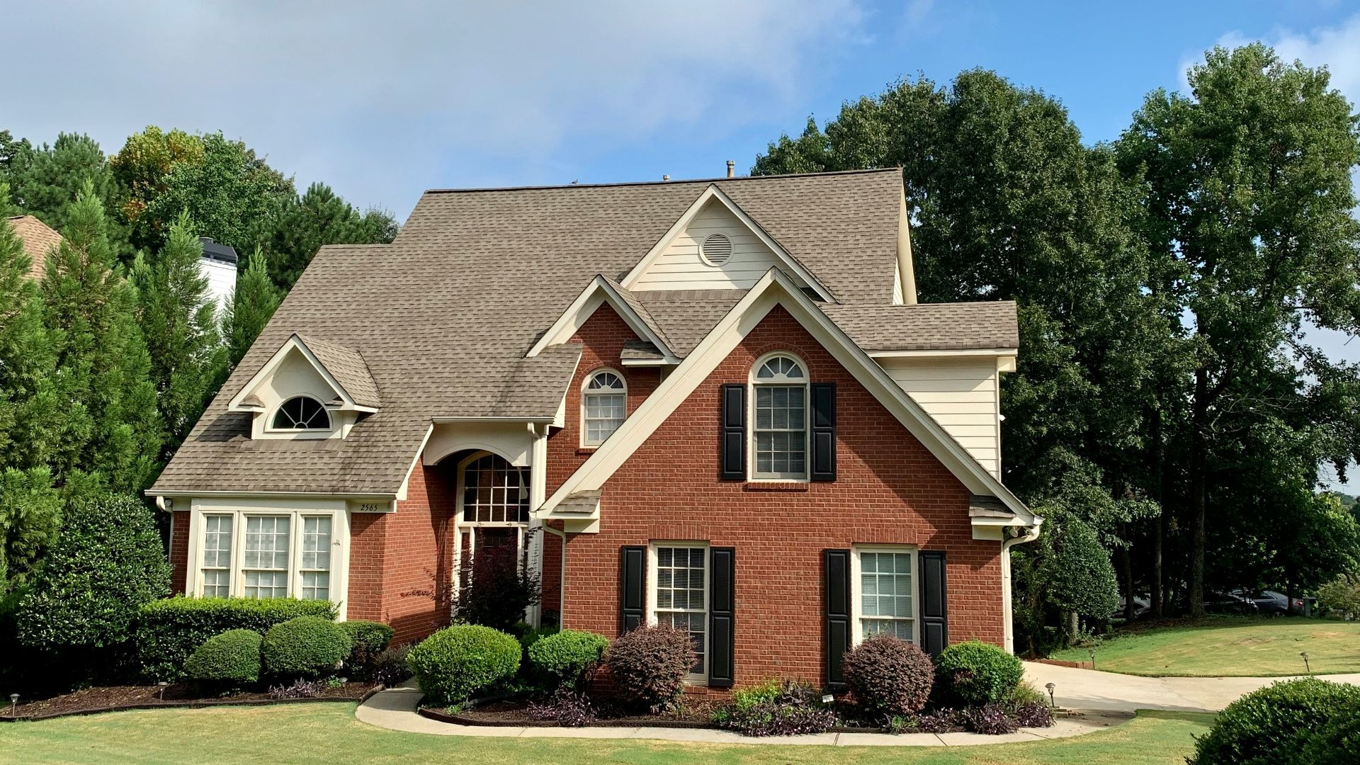 brown and white concrete house near green trees under blue sky during daytime
