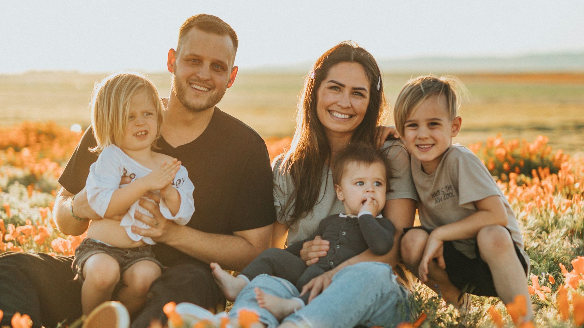 3 women and 2 men sitting on green grass field during daytime