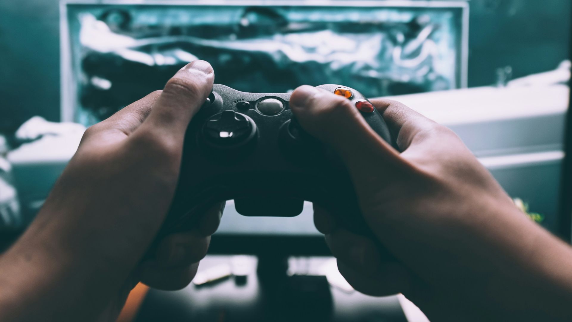 person holding game controller in-front of television