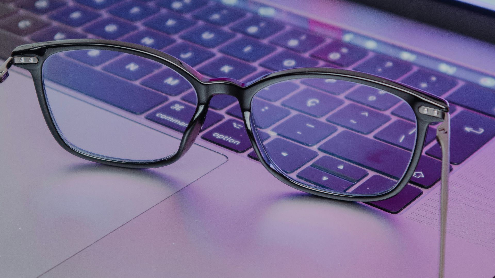 a pair of glasses sitting on top of a laptop keyboard