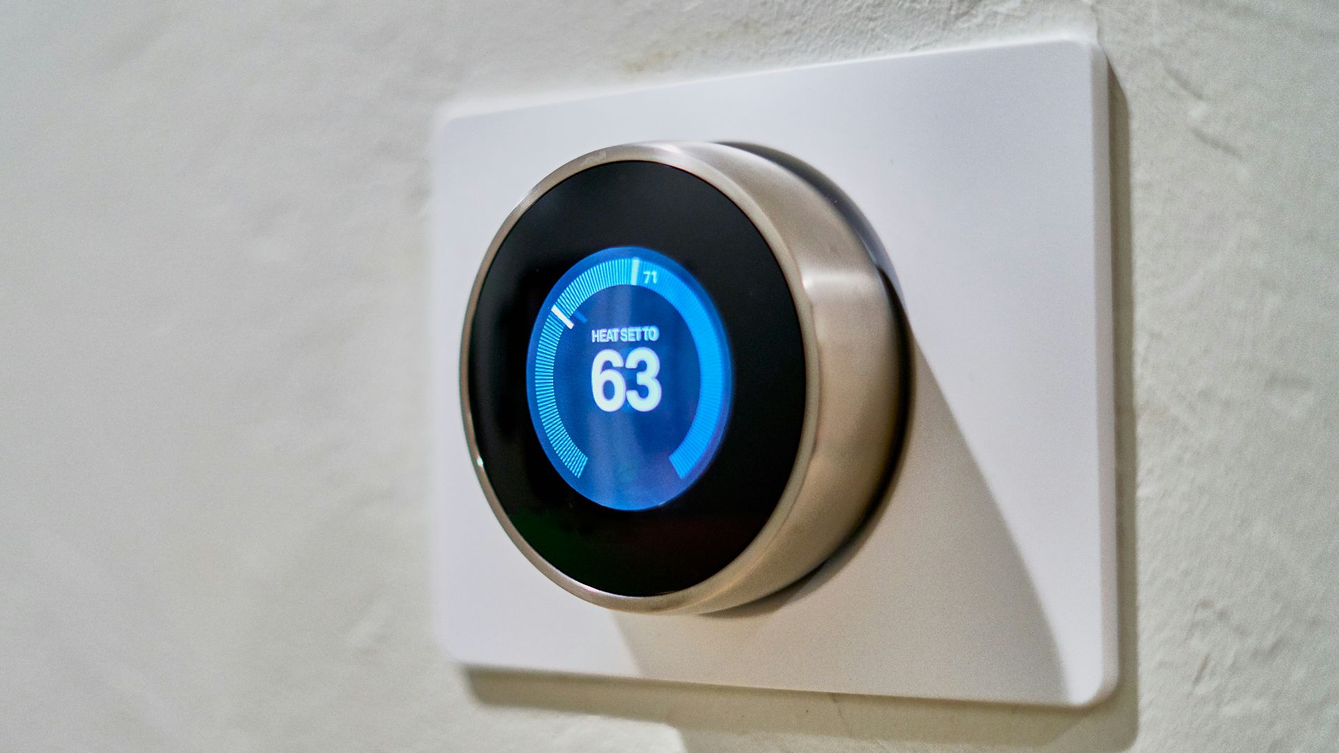 gray Nest thermostat displaying at 63